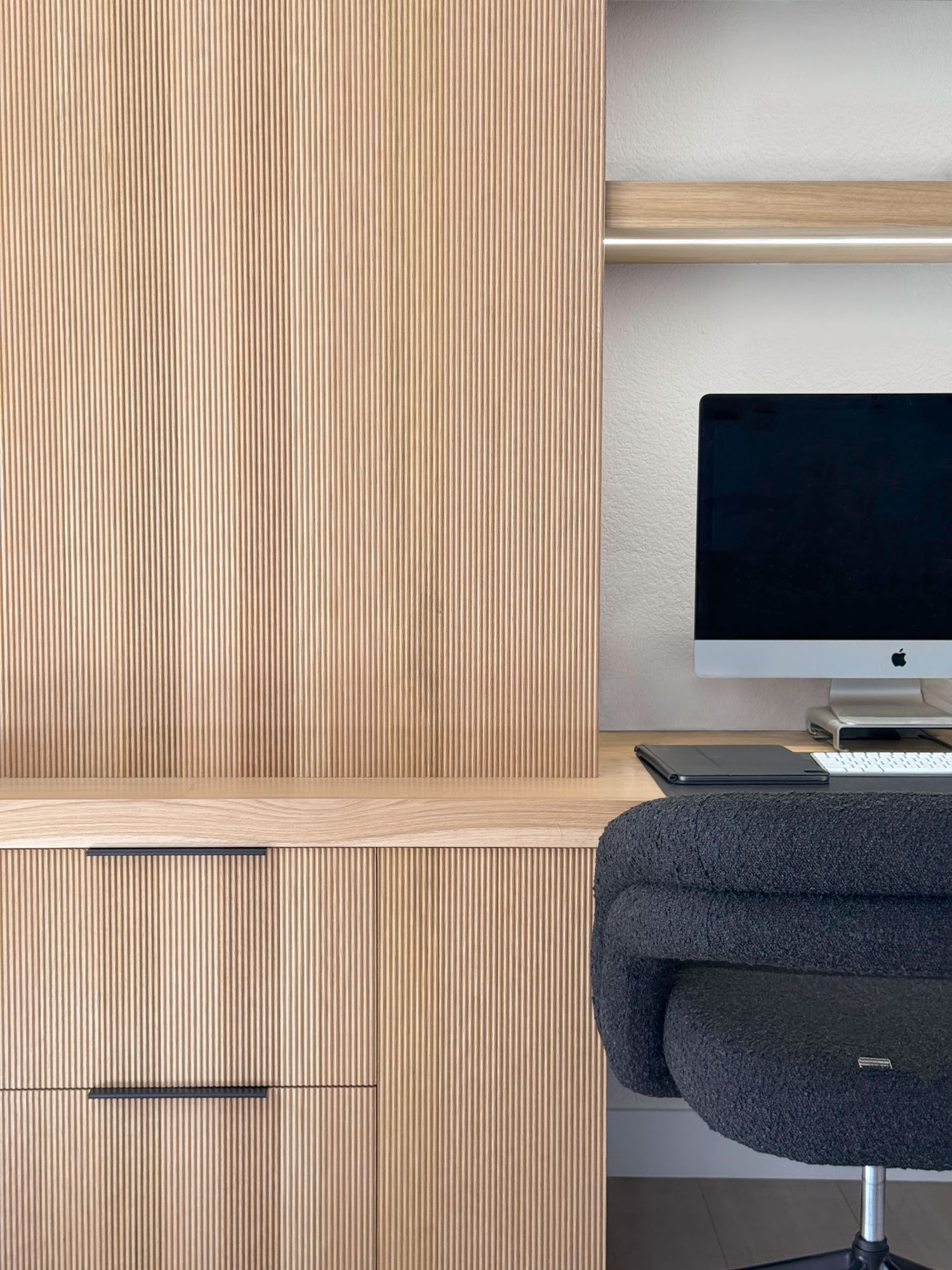 Built-in wooden desk area with ribbed panel details and dark office chair photographed in San Juan Capistrano, CA by interior photographer.
