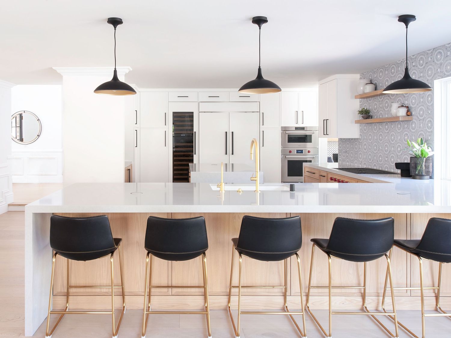 Interior Photographer photo of row of black modern bar stools along a white kitchen counter with pendant lighting and custom kitchen design.
