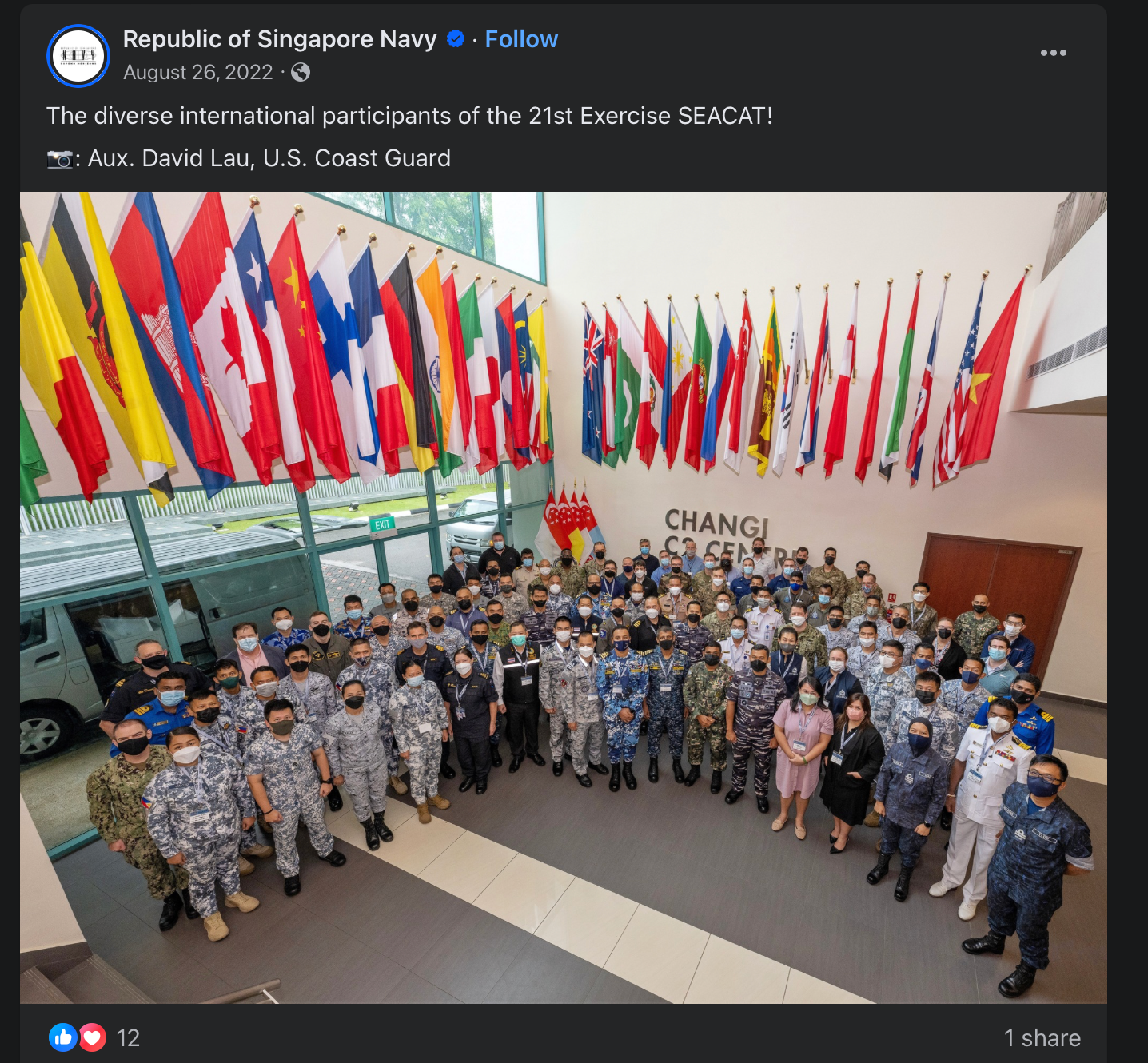 Large group of military personnel posing with international flags at Exercise SEACAT.