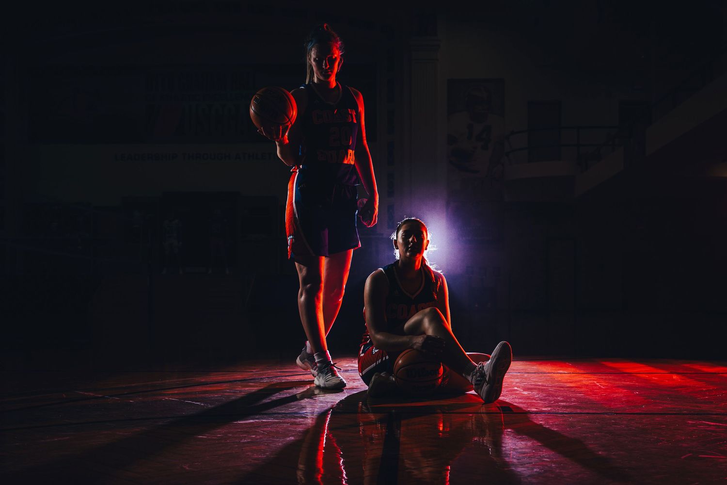 Dramatic silhouettes of performers in red stage lighting create artistic scene.