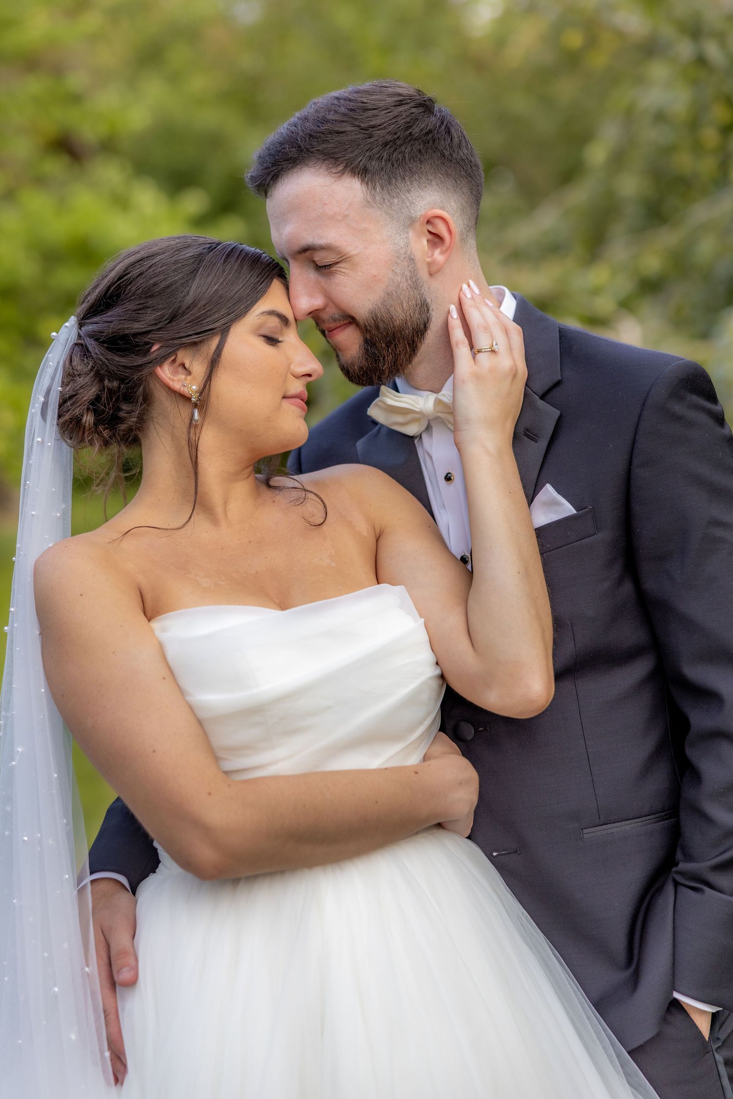 Intimate wedding portrait of couple sharing tender moment in garden setting.