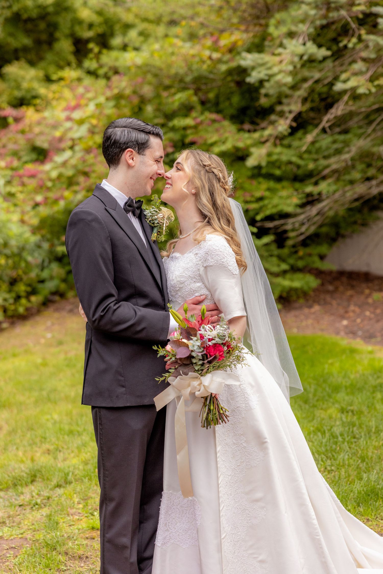 A romantic wedding portrait of a couple embracing in a garden setting with lush greenery and florals.
