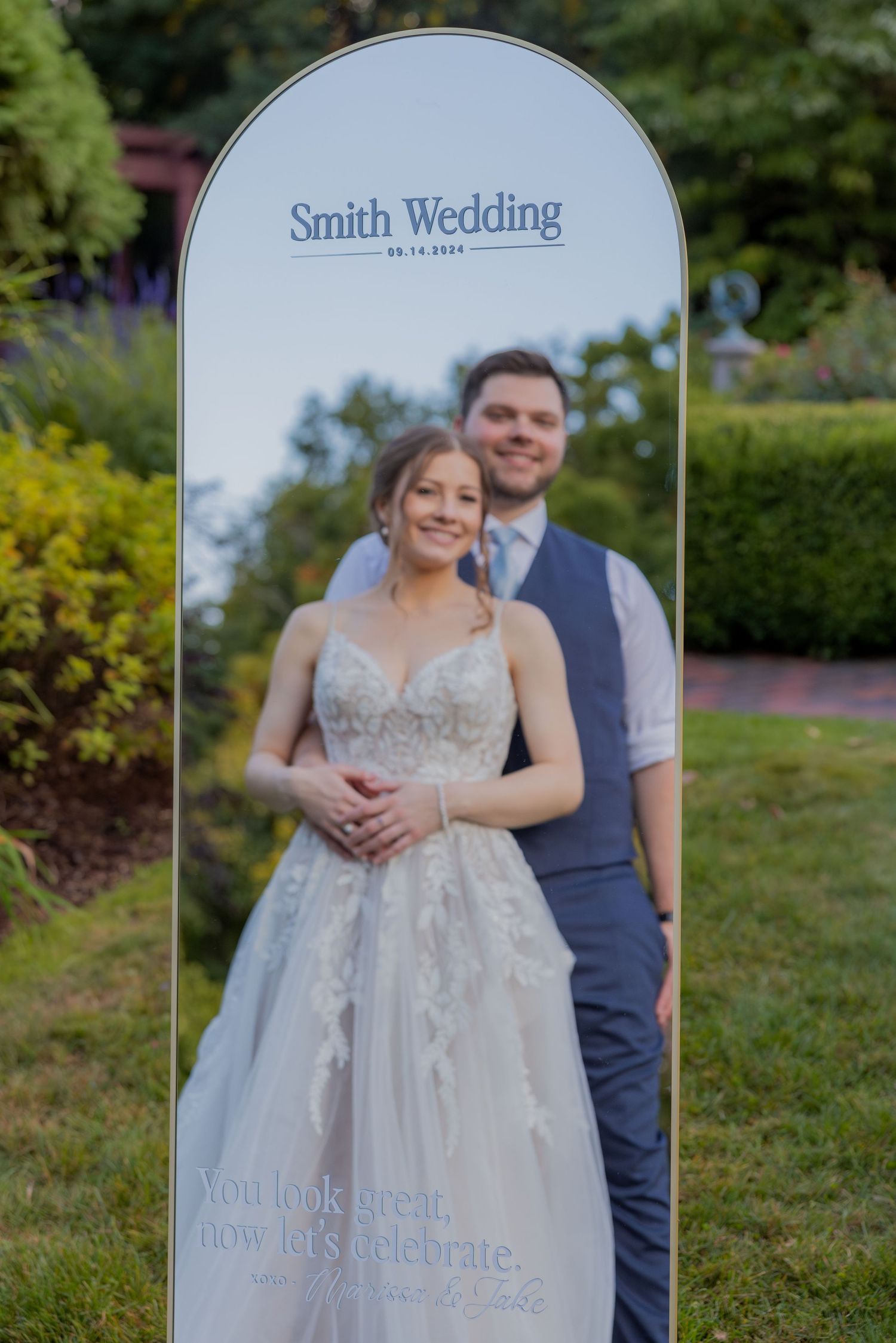 A decorative mirror displays a wedding portrait text overlay in a garden setting.