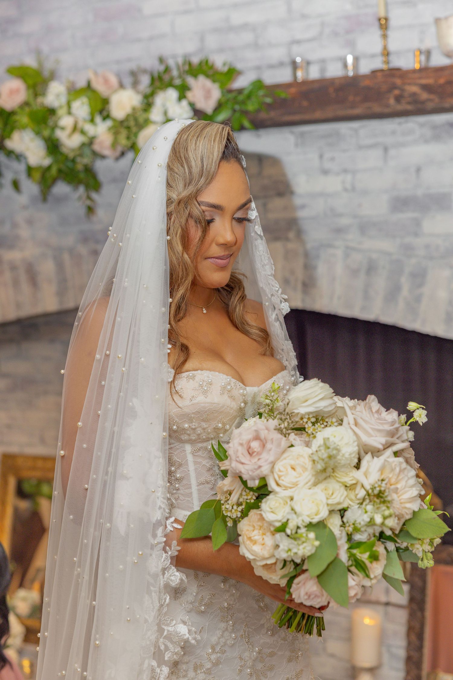 Detailed shot of bride with flowing veil holding elegant white and pink bouquet.