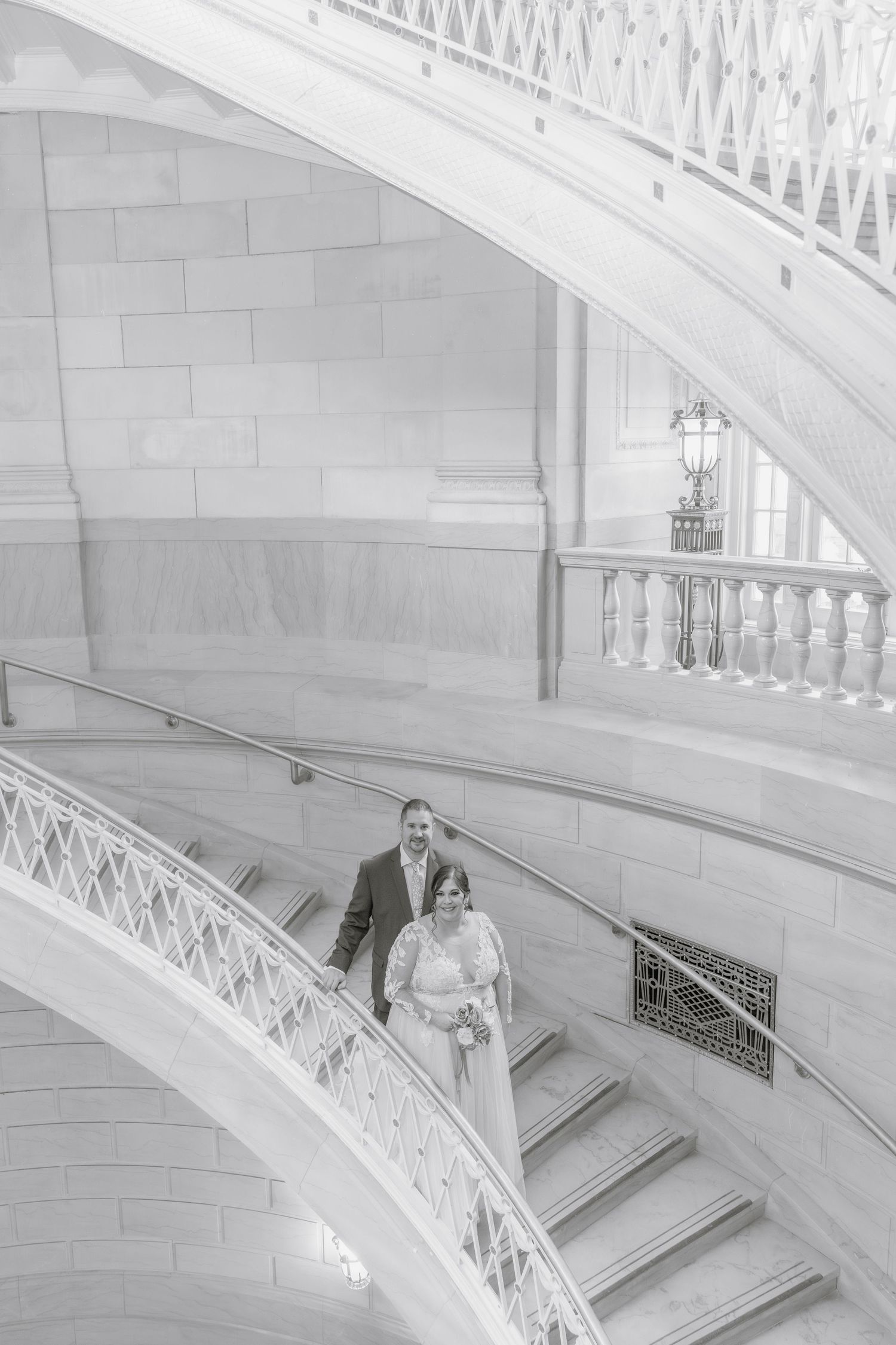 A classic black and white wedding photo on an elegant curved marble staircase.
