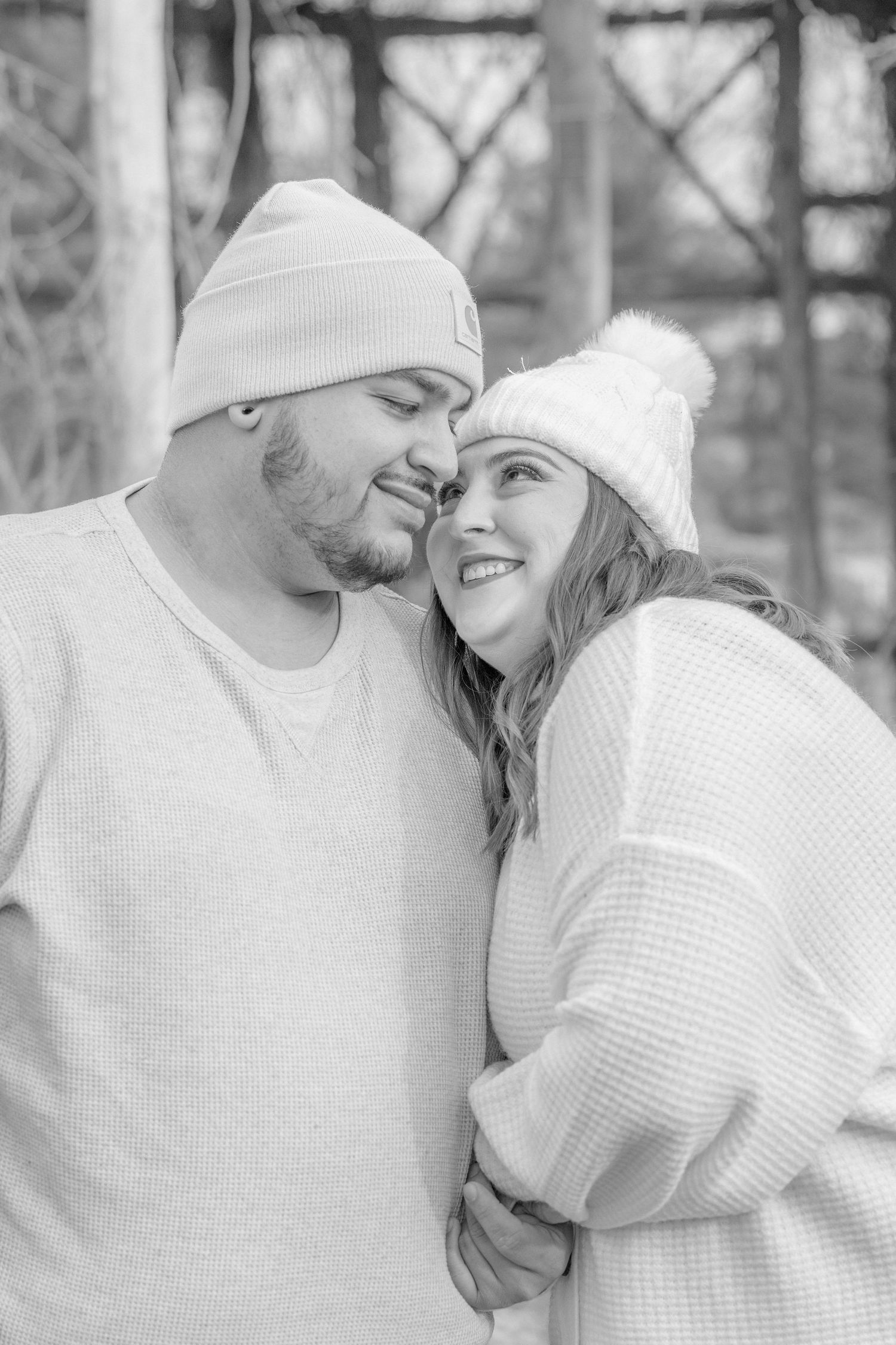 Black and white portrait of a couple in matching cream sweaters sharing a tender moment.