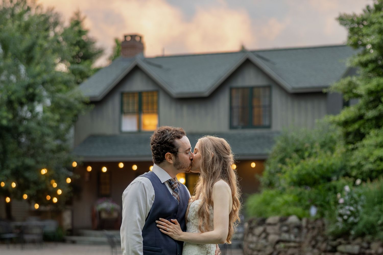 A series of romantic outdoor wedding photos at sunset with glowing string lights in a rustic setting.