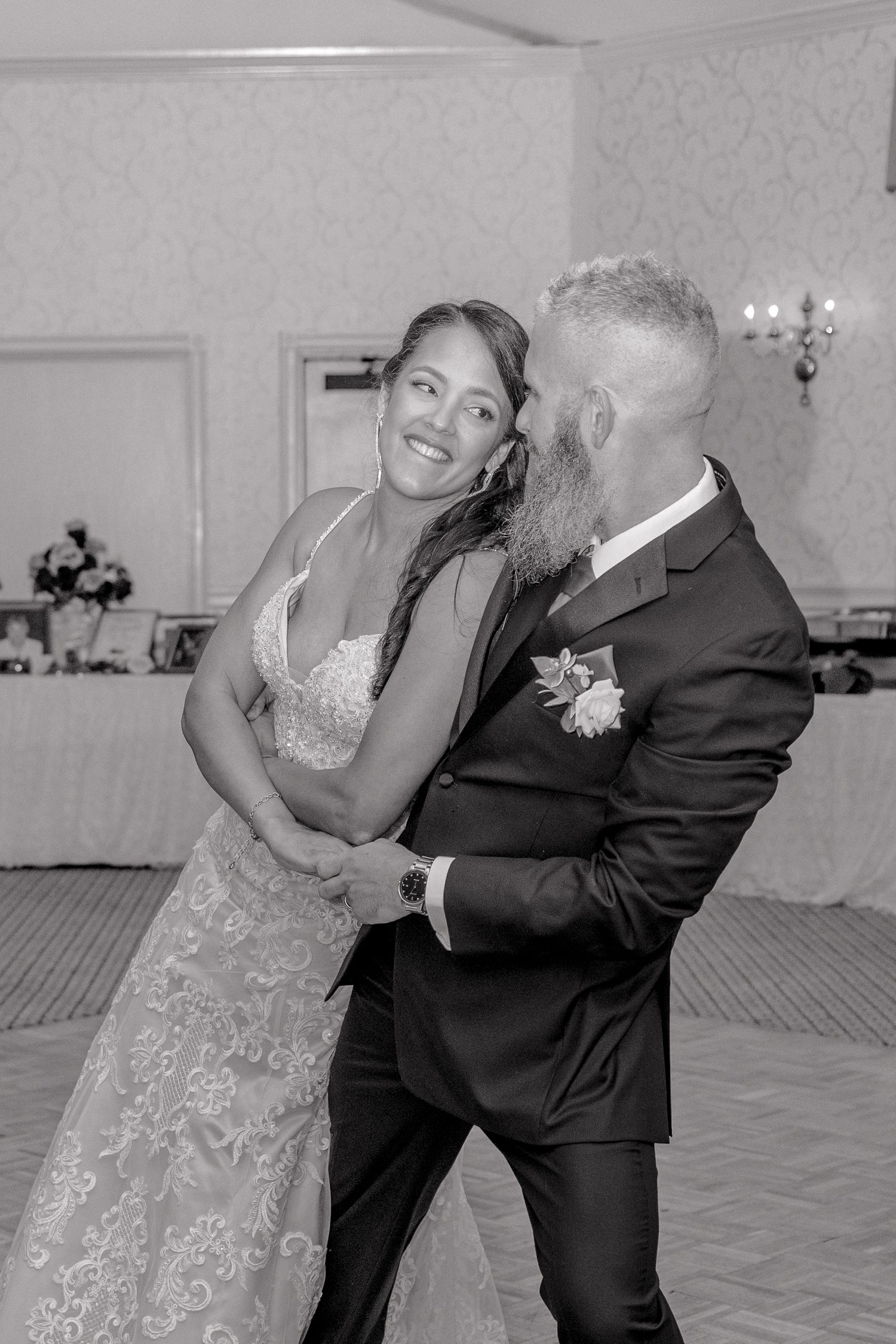 Couple dances together in formal attire at wedding reception venue.
