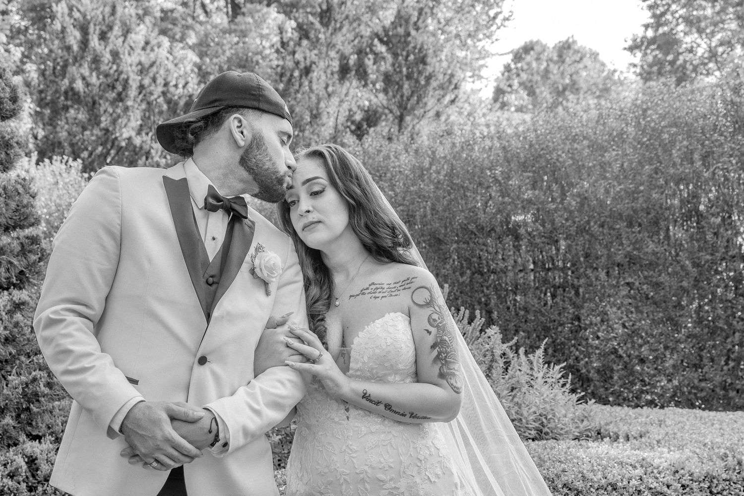 Black and white portrait of couple sharing intimate moment in garden setting.