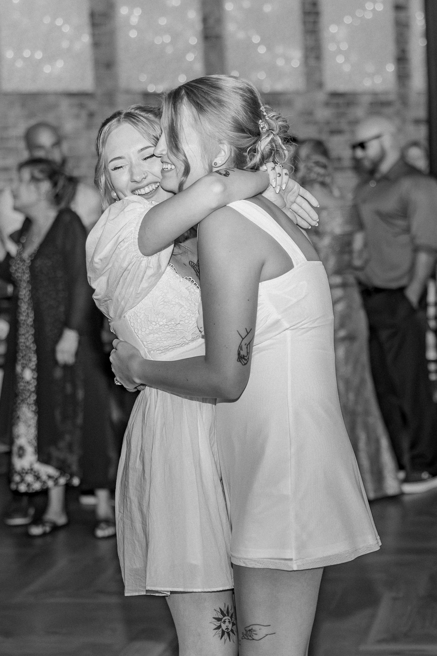 A series of four black and white photos showing two people in white dresses dancing and embracing at a wedding reception.