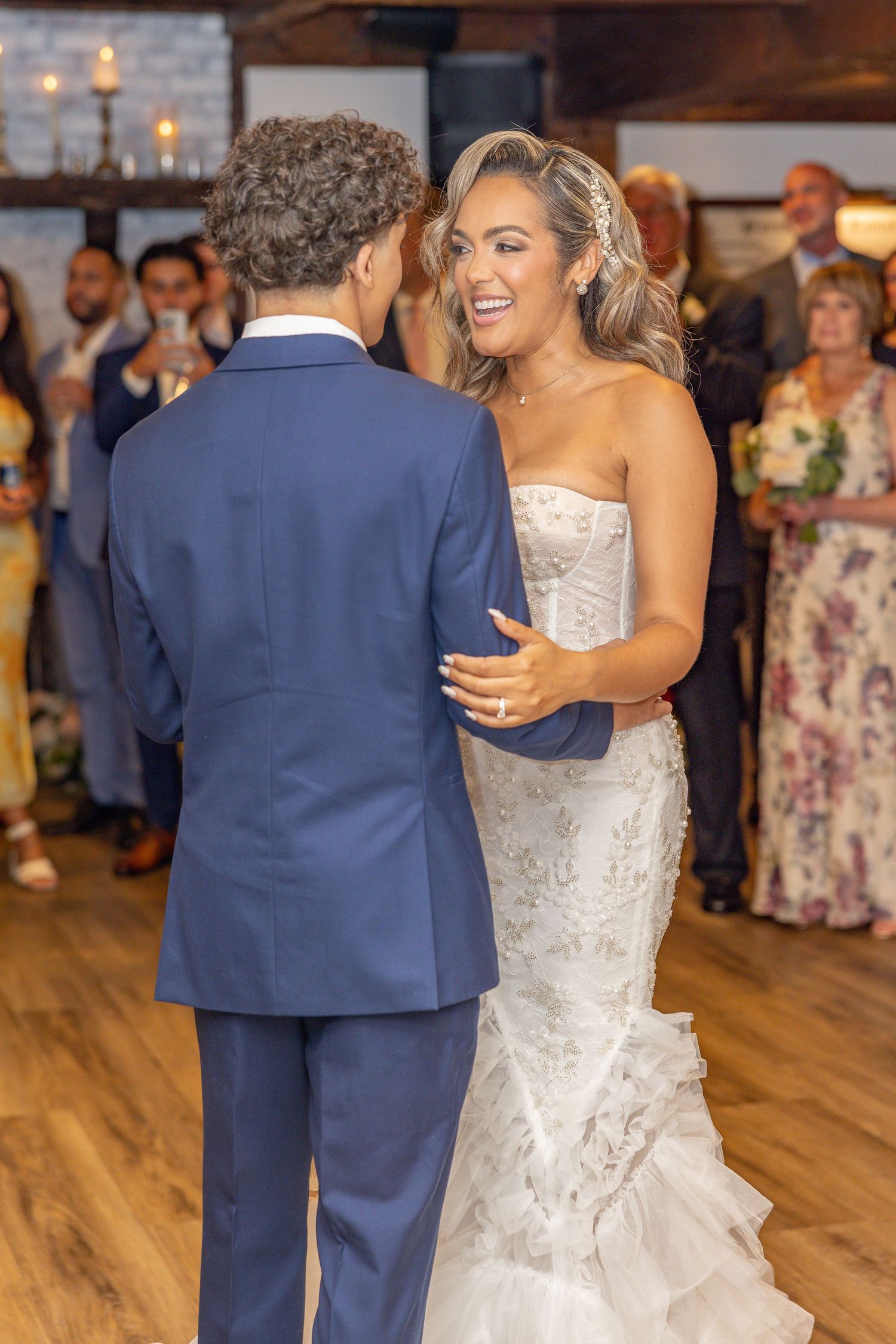 A romantic first dance moment captured at a wedding reception with candlelit ambiance and wooden floors.