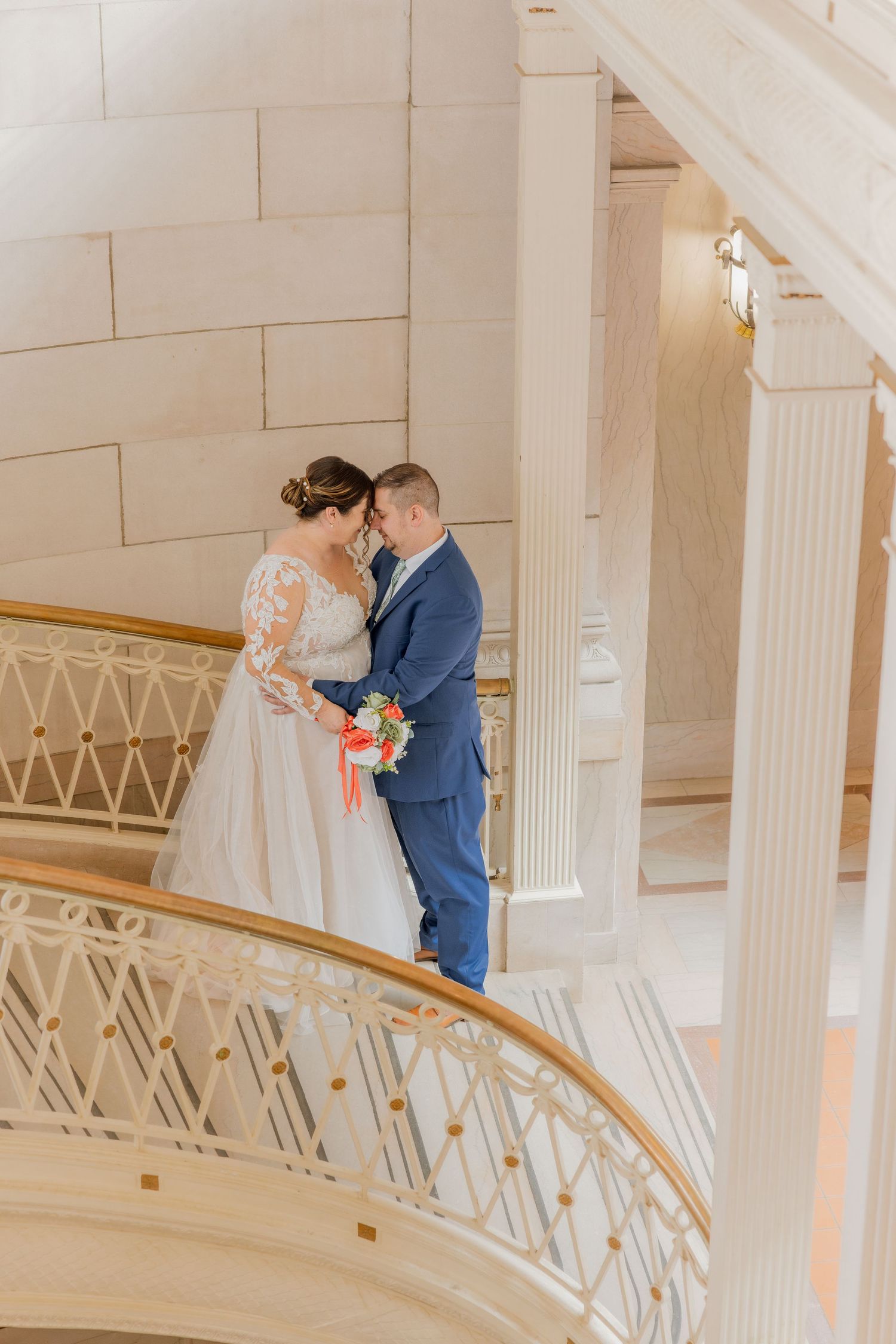 Intimate wedding moment captured on an ornate white marble staircase.