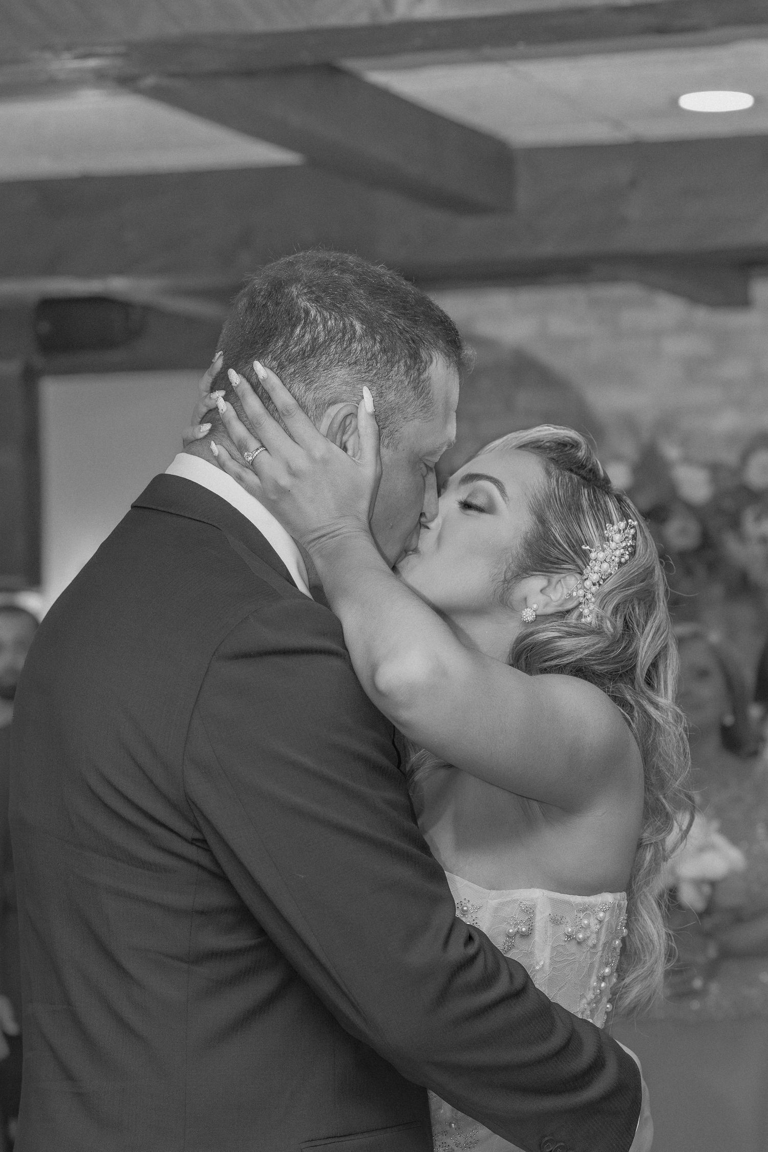 Intimate wedding kiss captured in black and white with rustic backdrop.