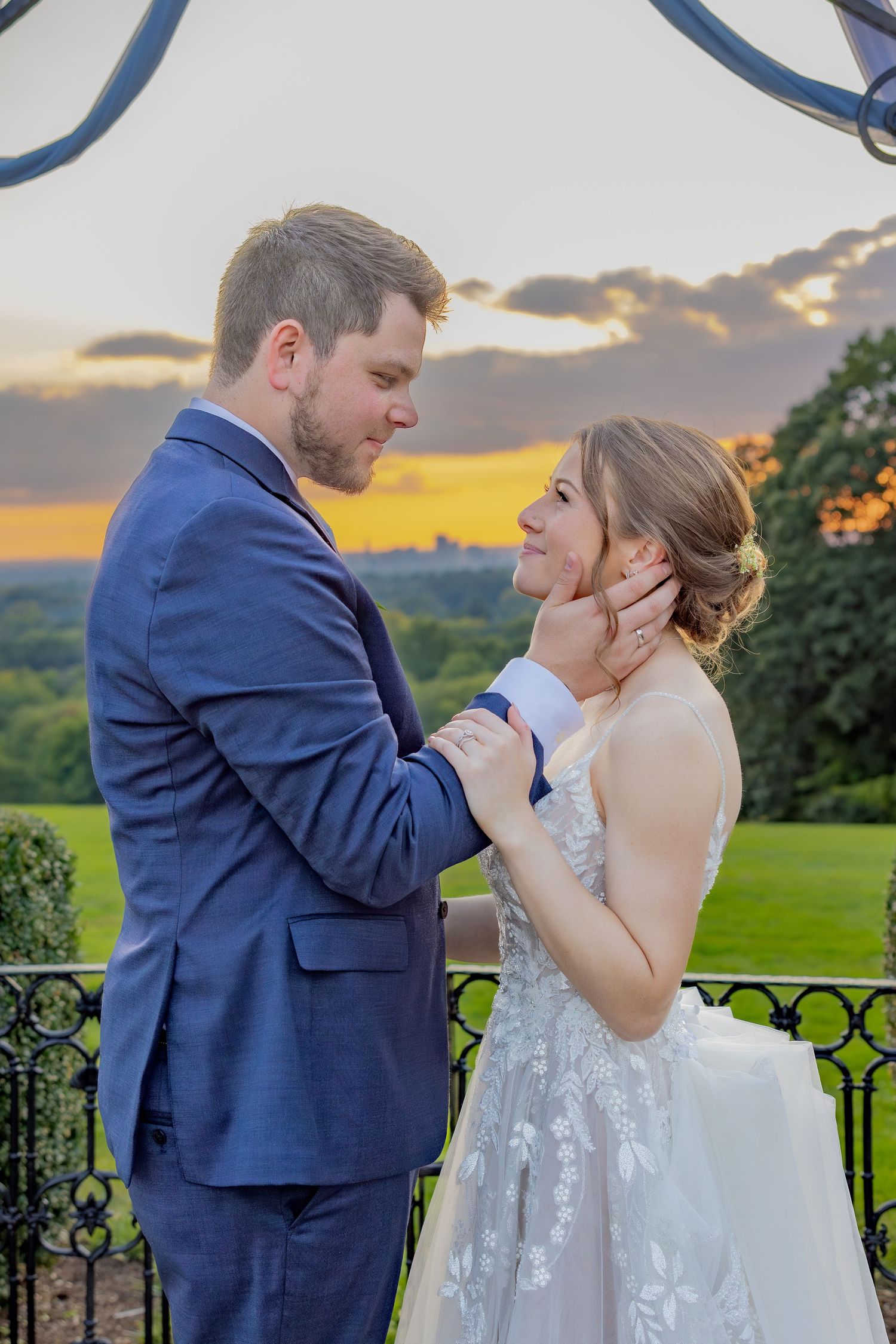 A romantic sunset portrait of newlyweds embracing outdoors against an orange sky.