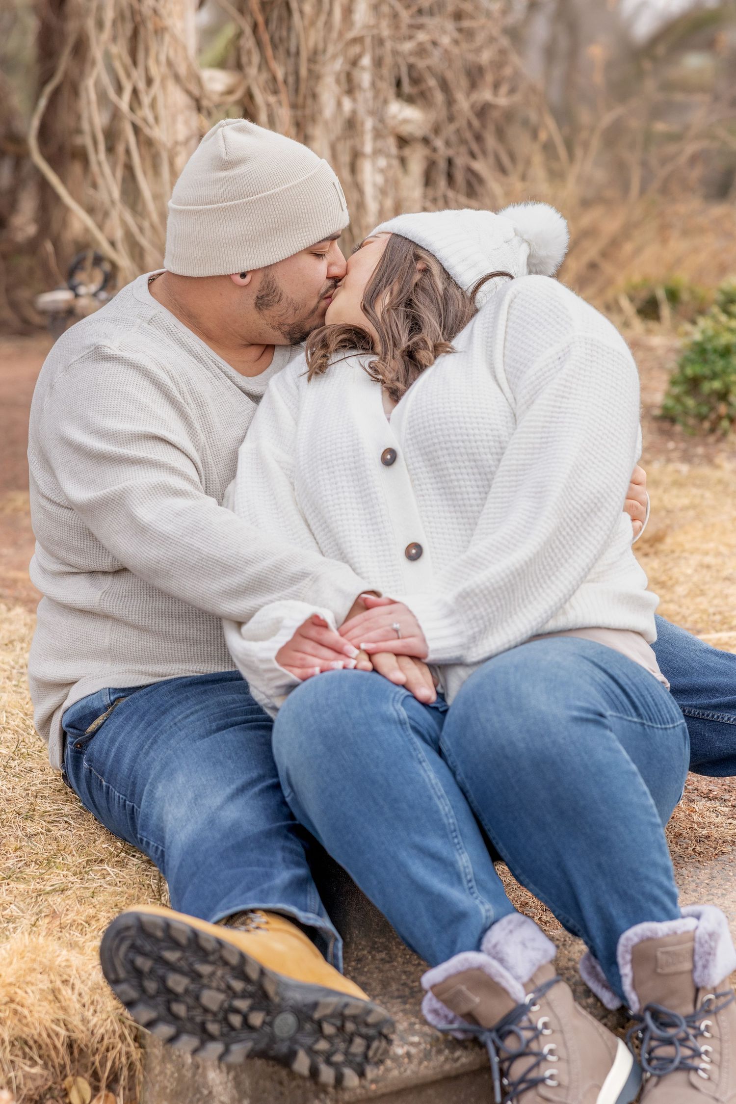 Couple in cozy winter wear share an intimate moment while sitting together outdoors.