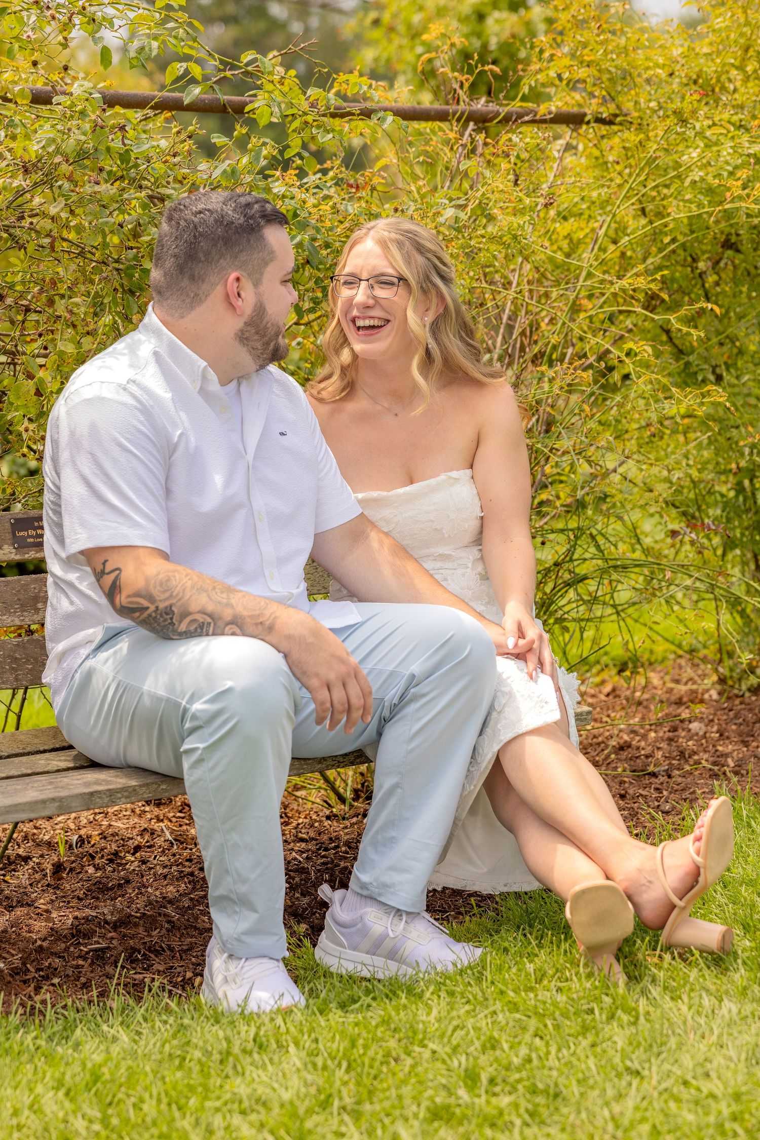 A joyful moment shared between a couple sitting on a bench in a garden setting.