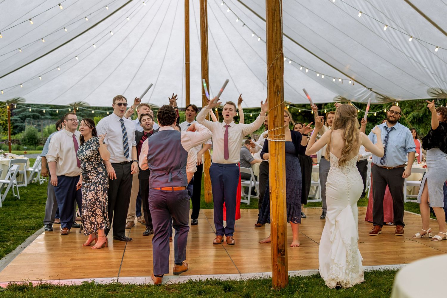 Rain droplets create a magical atmosphere on the clear tent covering while wedding guests dance and celebrate underneath.