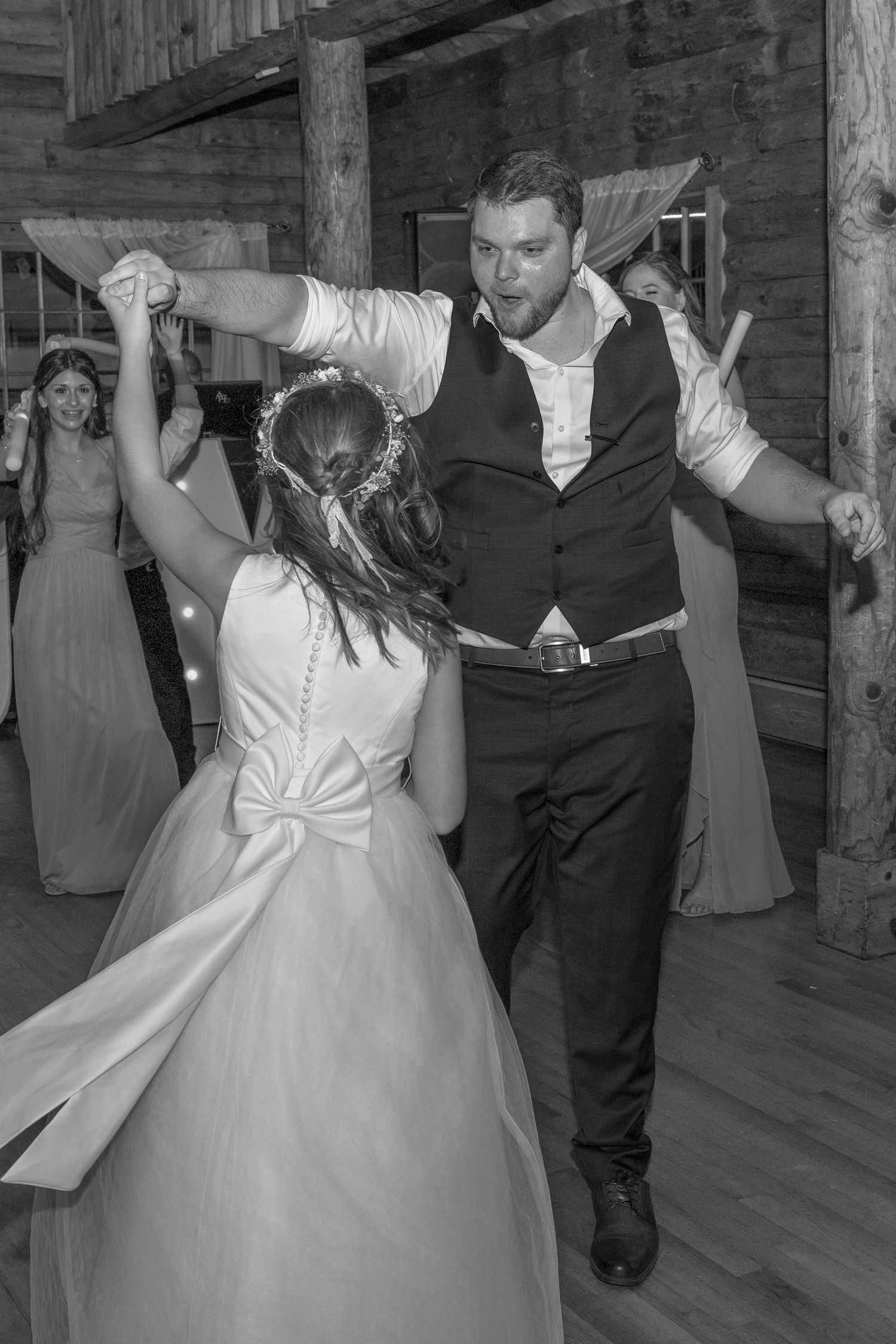 Dancing celebration in a rustic barn venue captured in black and white photography.