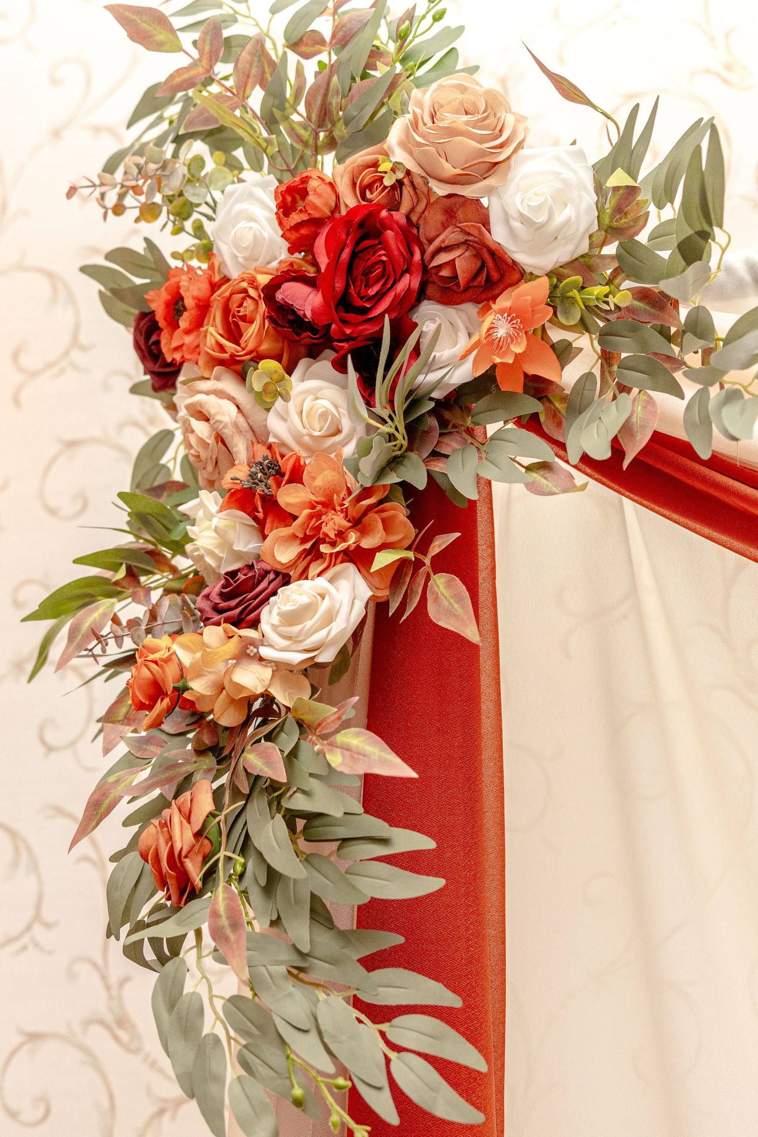 Elegant floral arrangement with coral, white and red roses adorned with eucalyptus leaves.