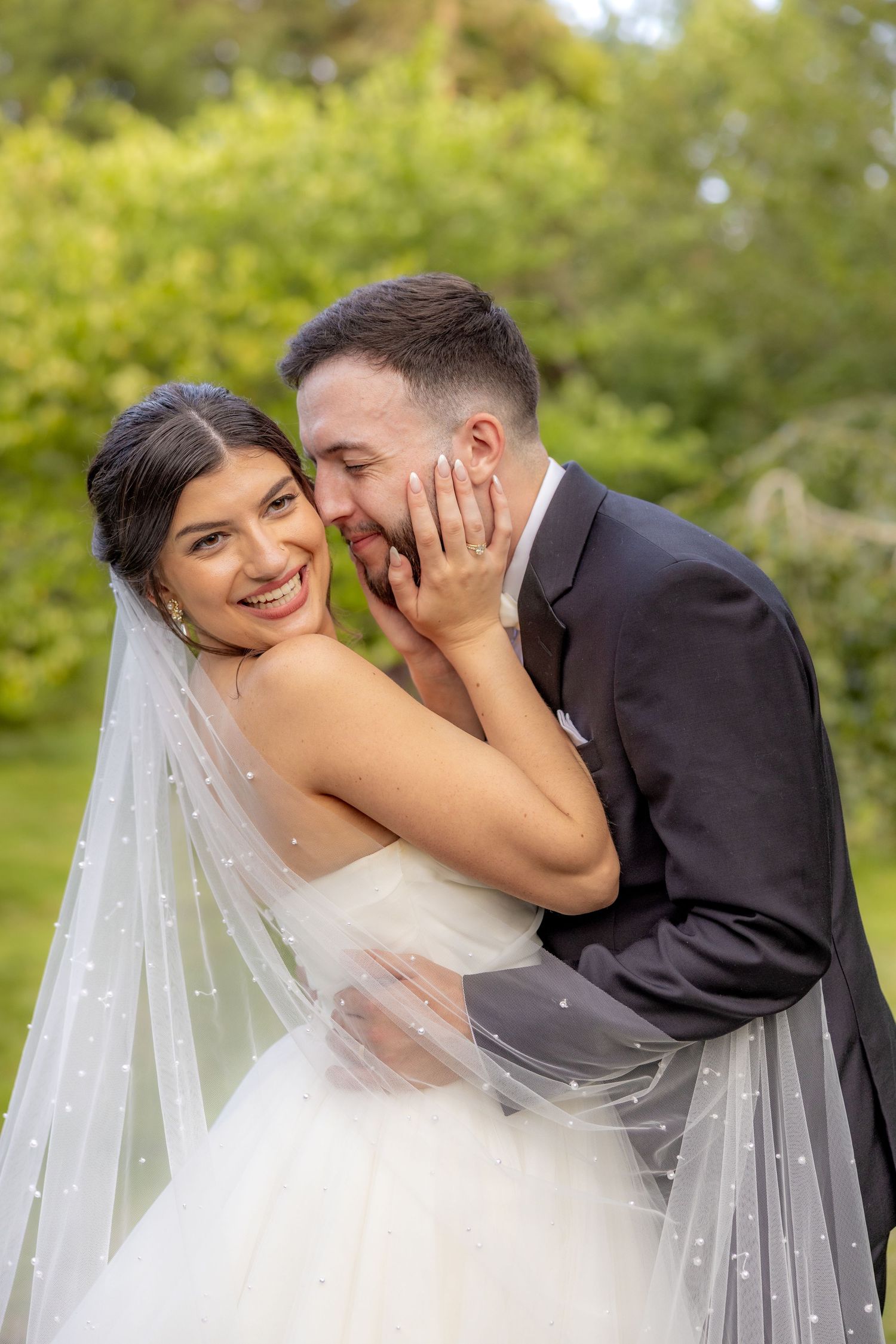 Happy newlyweds share an intimate moment outdoors in their wedding attire.