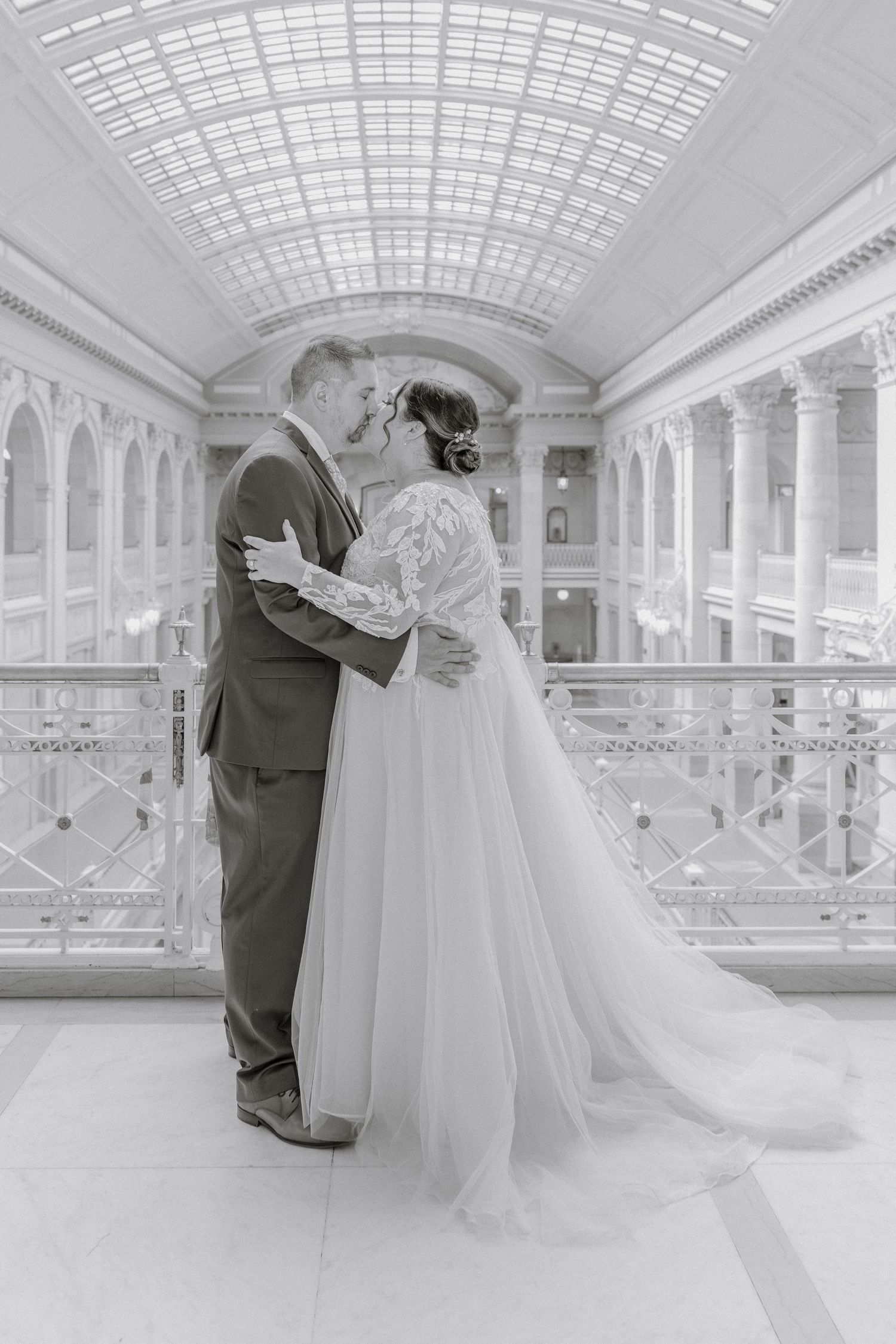 Black and white wedding portrait in elegant marble hall with skylight ceiling.