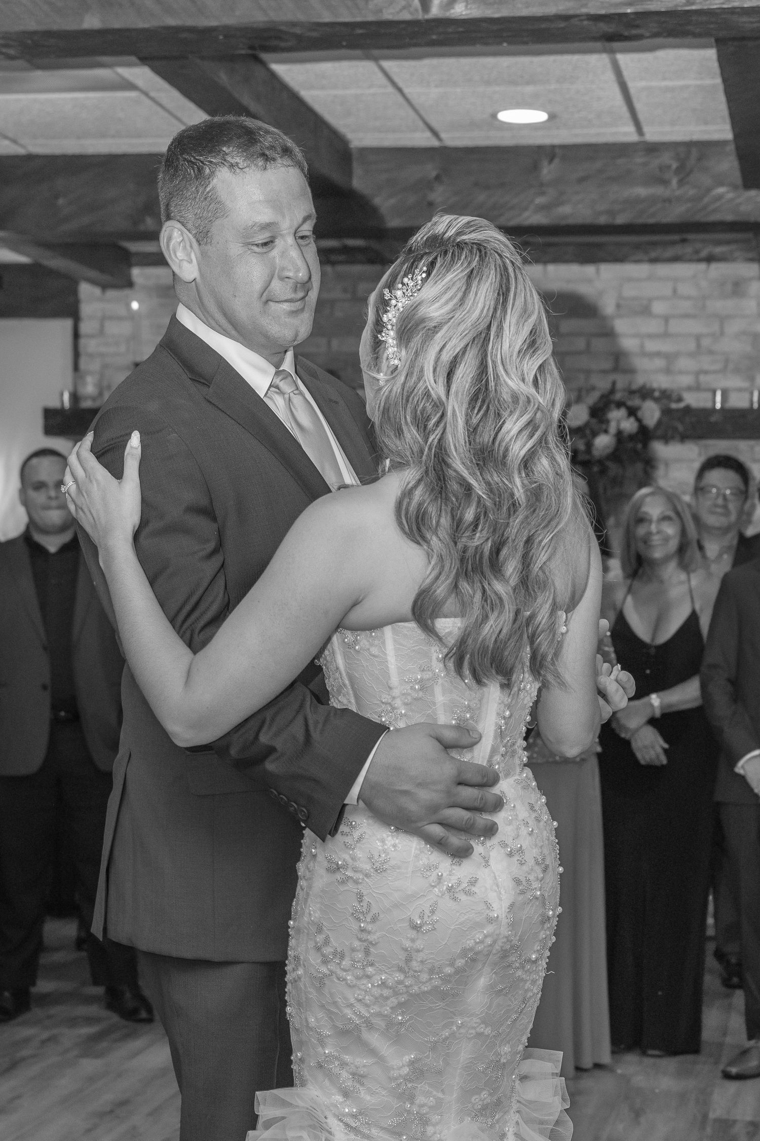 Newlyweds share an intimate dance moment on a wooden dance floor at their indoor wedding reception.