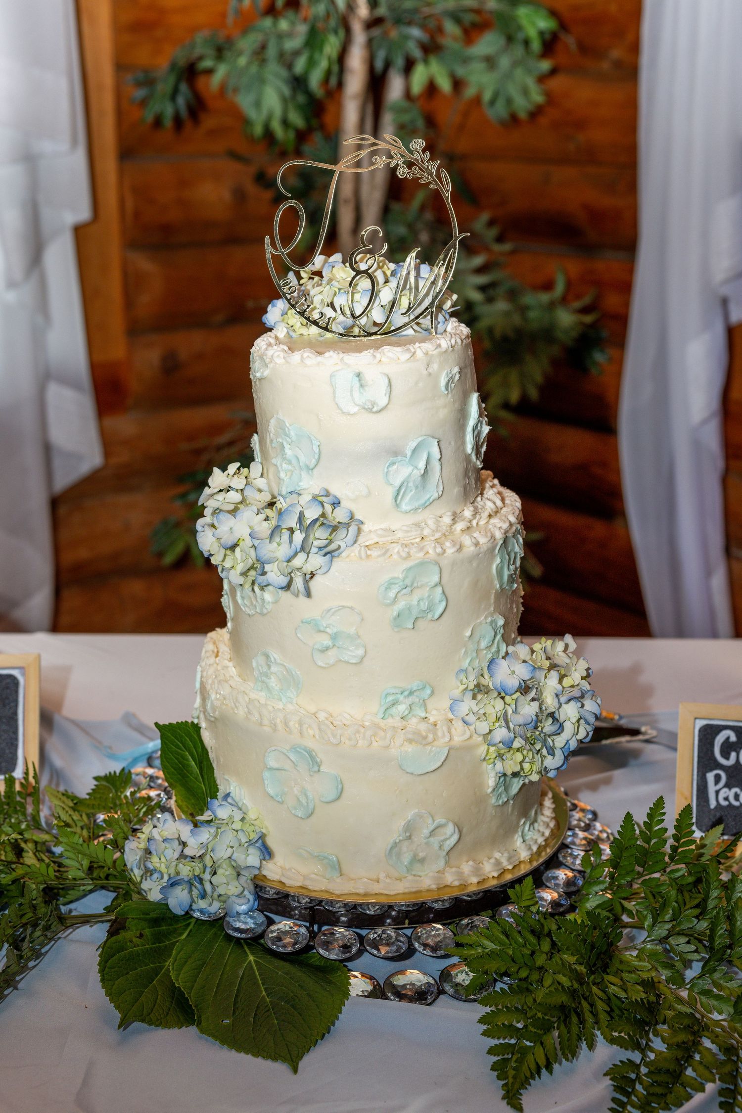 Elegant four-tier white wedding cake decorated with blue butterflies and hydrangeas on display.