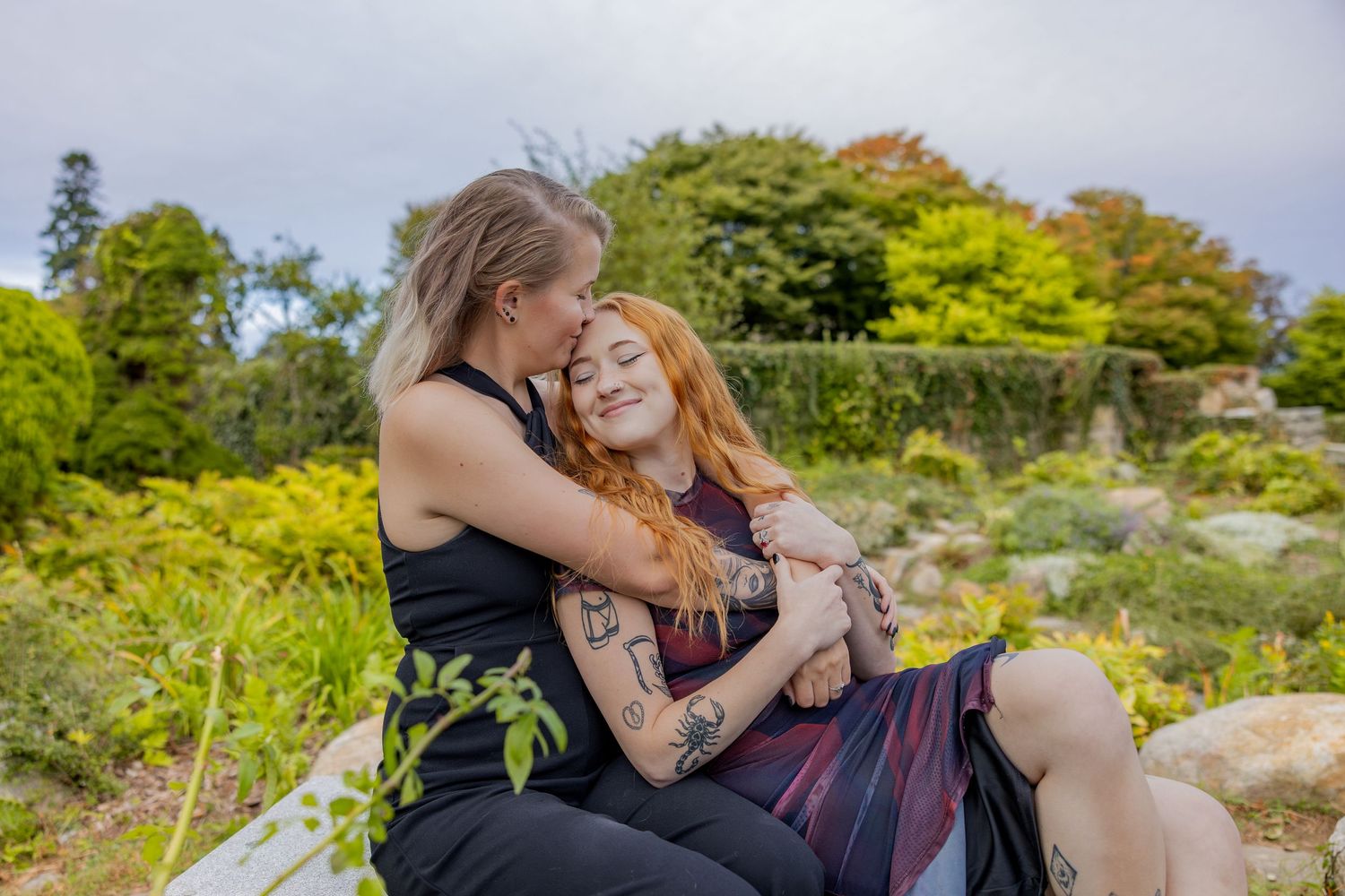 Couple embracing outdoors in a garden setting with natural lighting and greenery in the background.