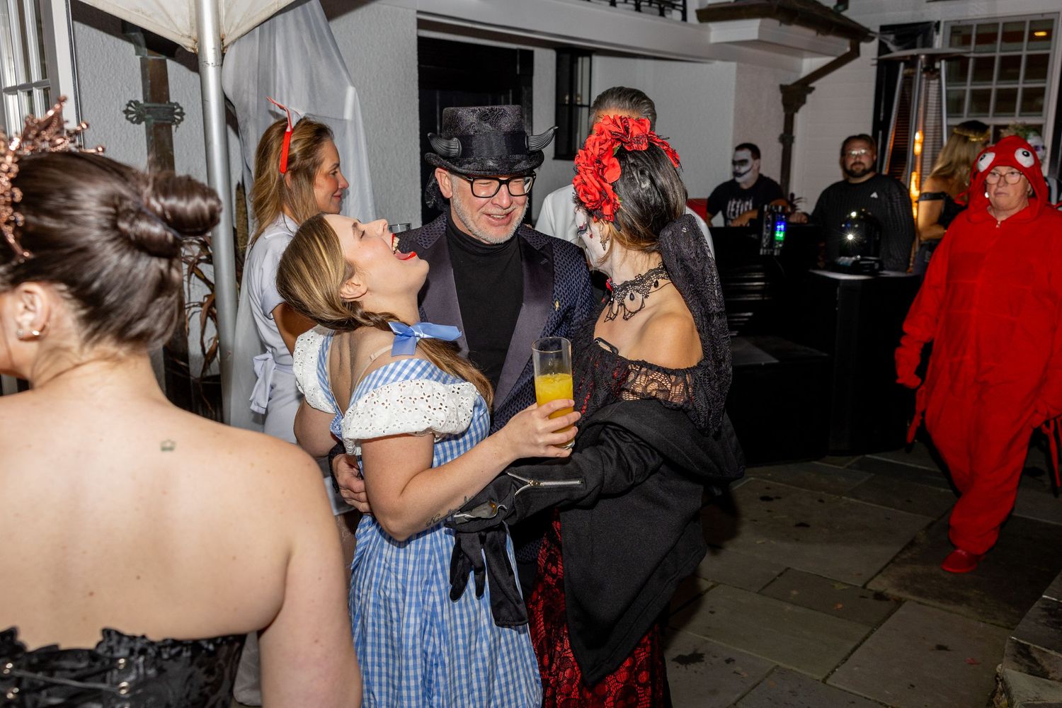 Costumed partygoers in Halloween attire socializing at indoor gathering.