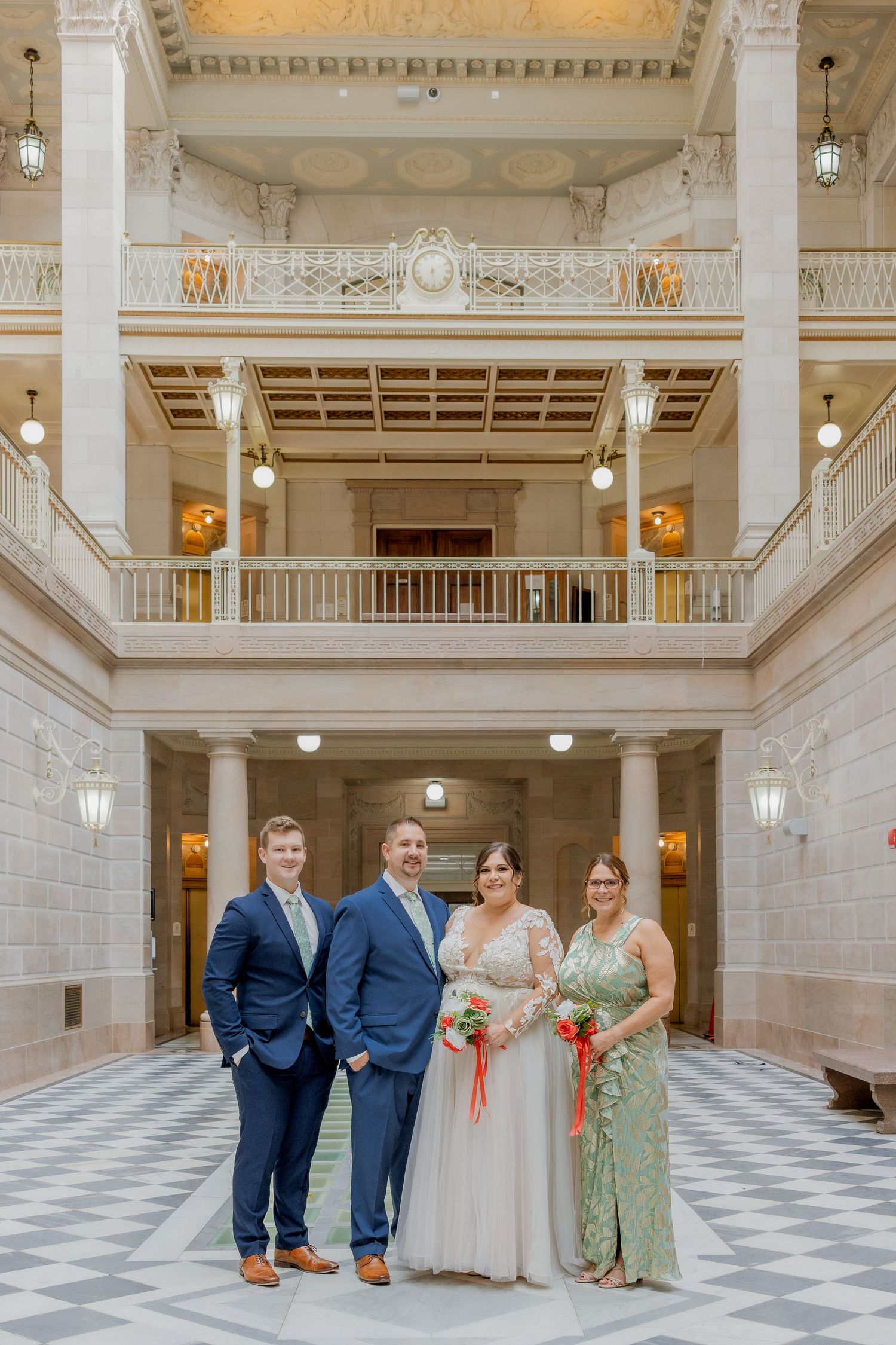 Wedding party poses in grand marble hall with classical architectural details.