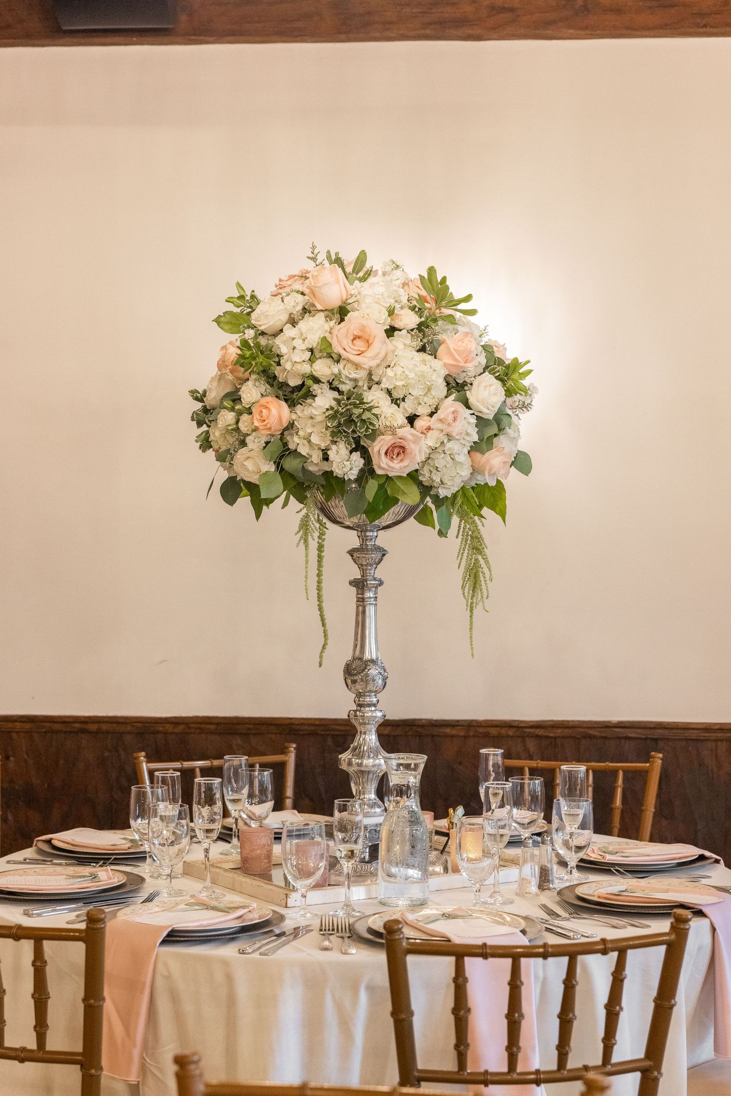 Elegant wedding centerpiece with pink and white flowers on silver pedestal.