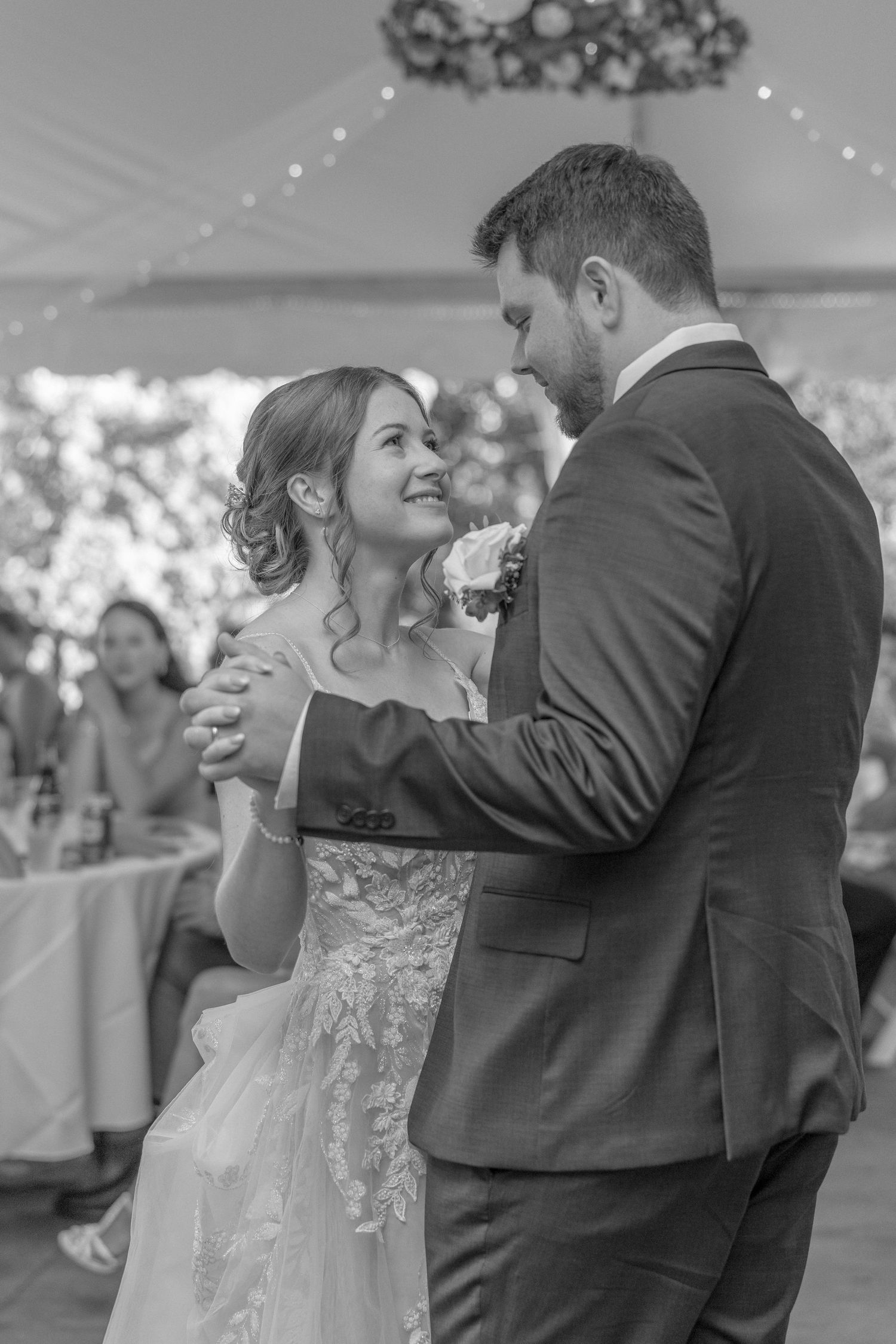 Newlyweds share a romantic first dance under a decorated tent ceiling at their wedding reception.