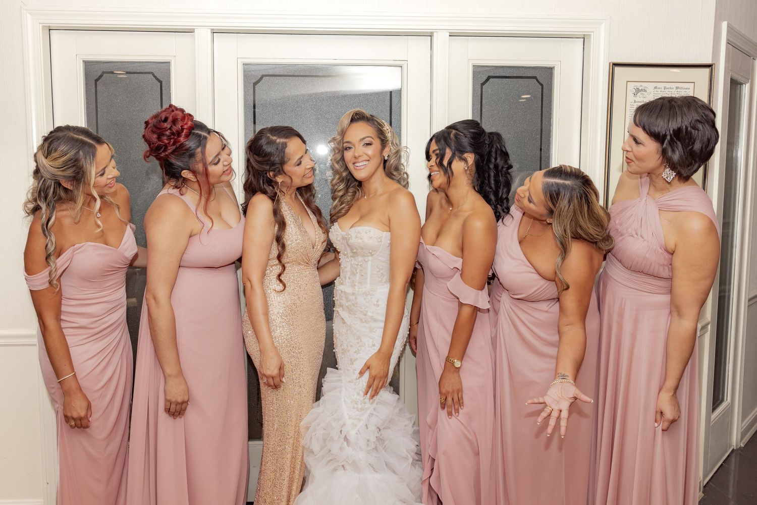 Wedding party poses in pink bridesmaid dresses and white bridal gown.