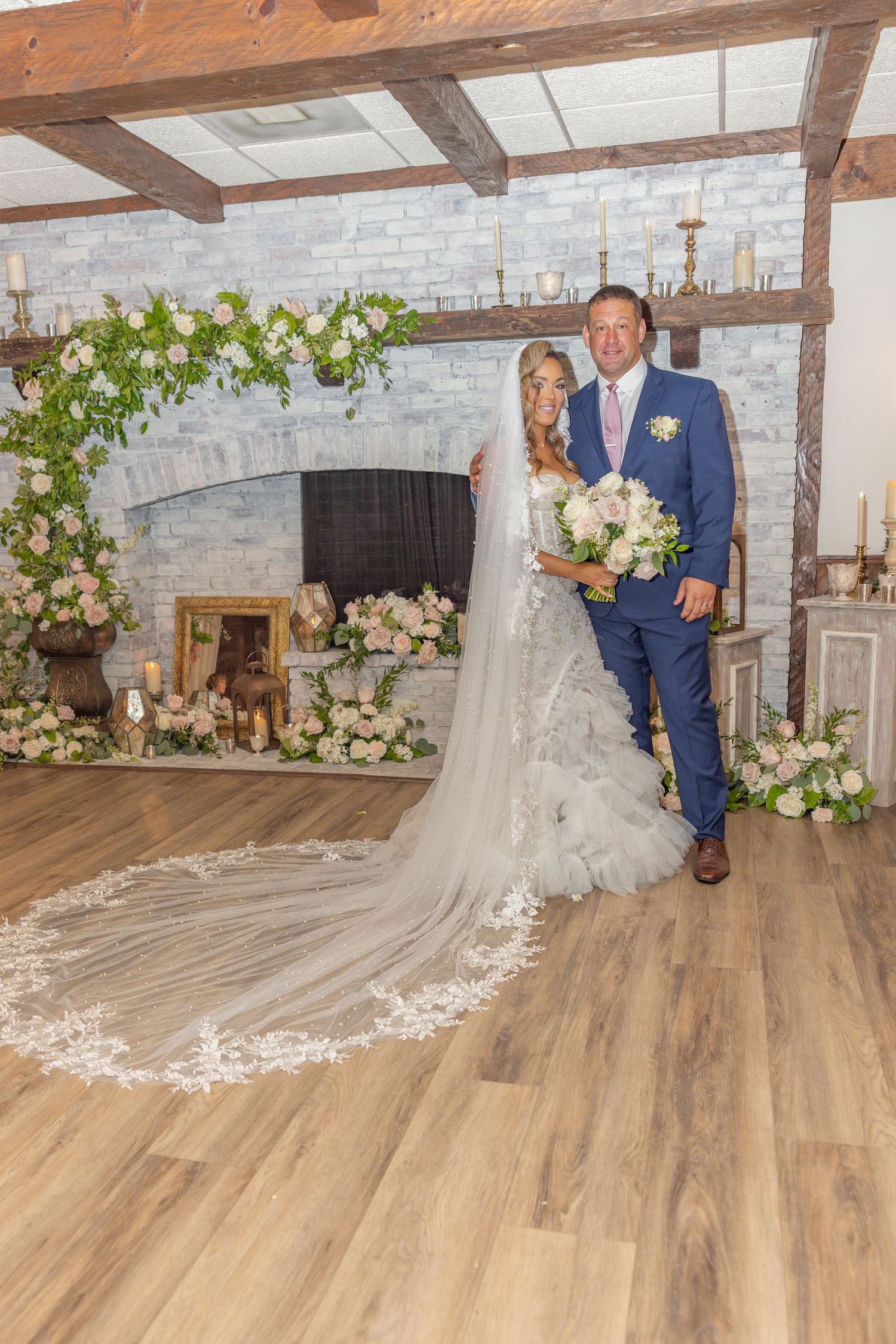 Wedding couple poses in rustic venue with exposed brick and floral decorations.