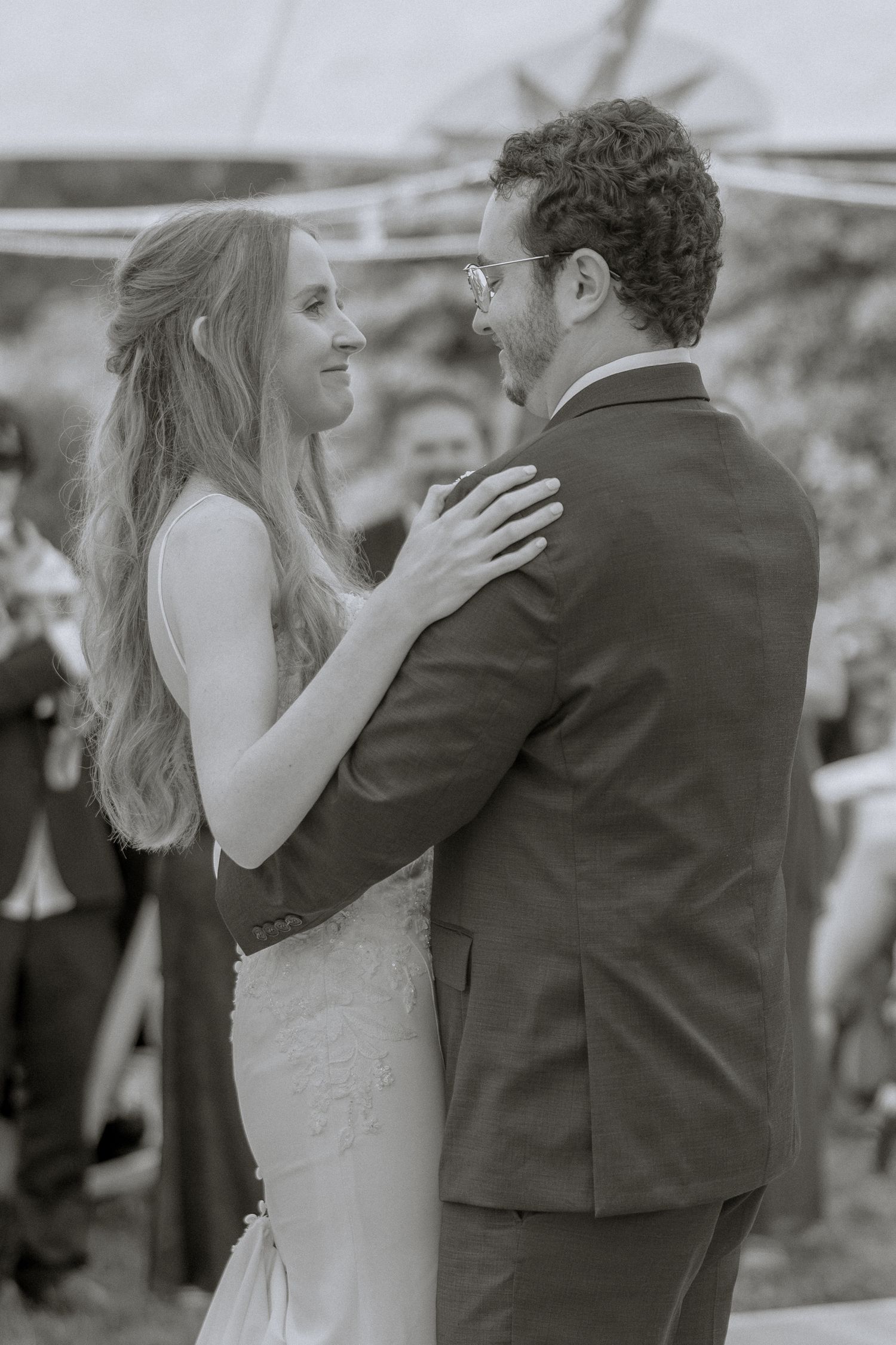 Happy bride and groom share an intimate moment during their wedding celebration in black and white.