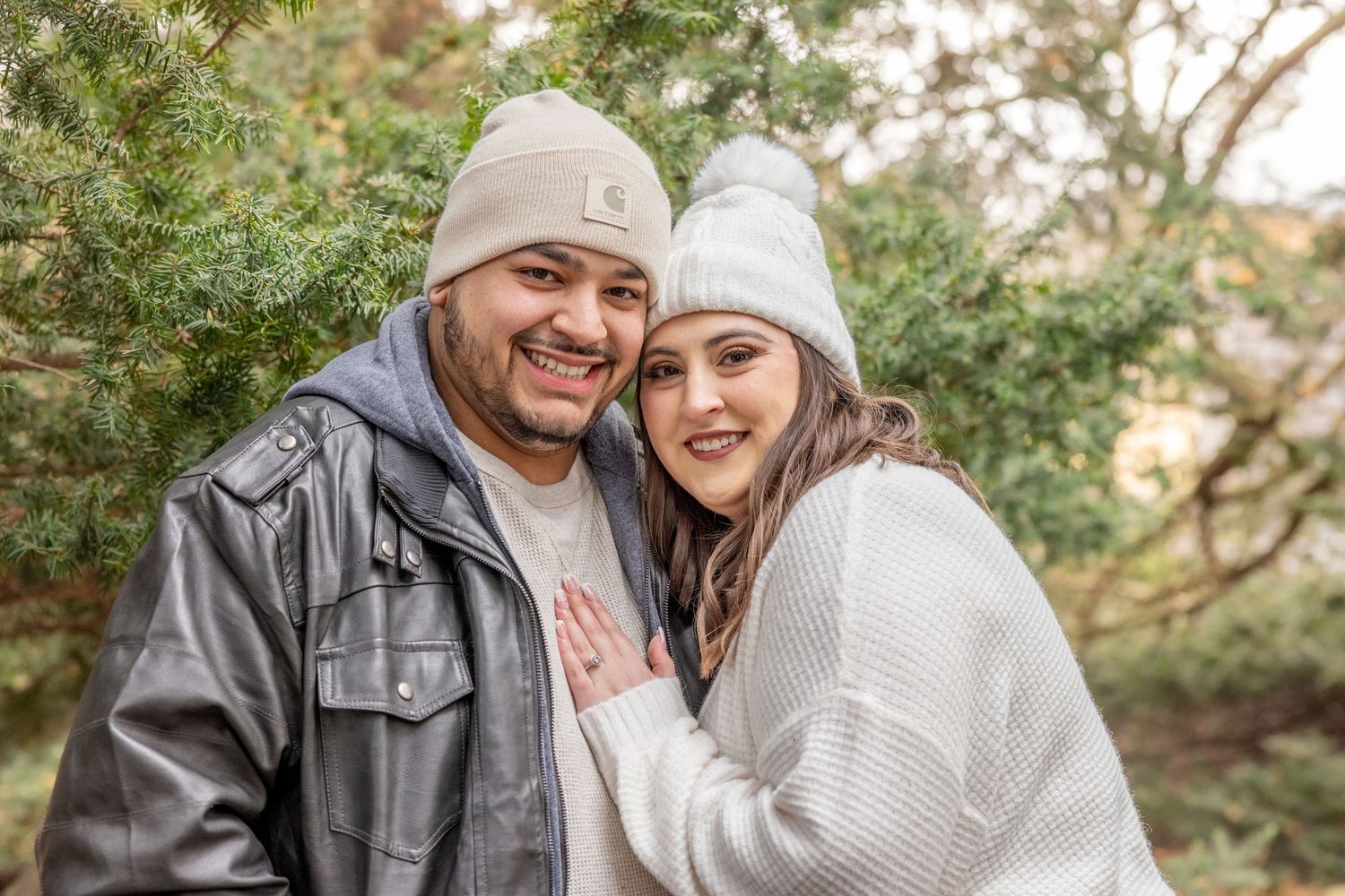 A couple in winter clothing sharing a sweet moment outdoors among autumn trees.