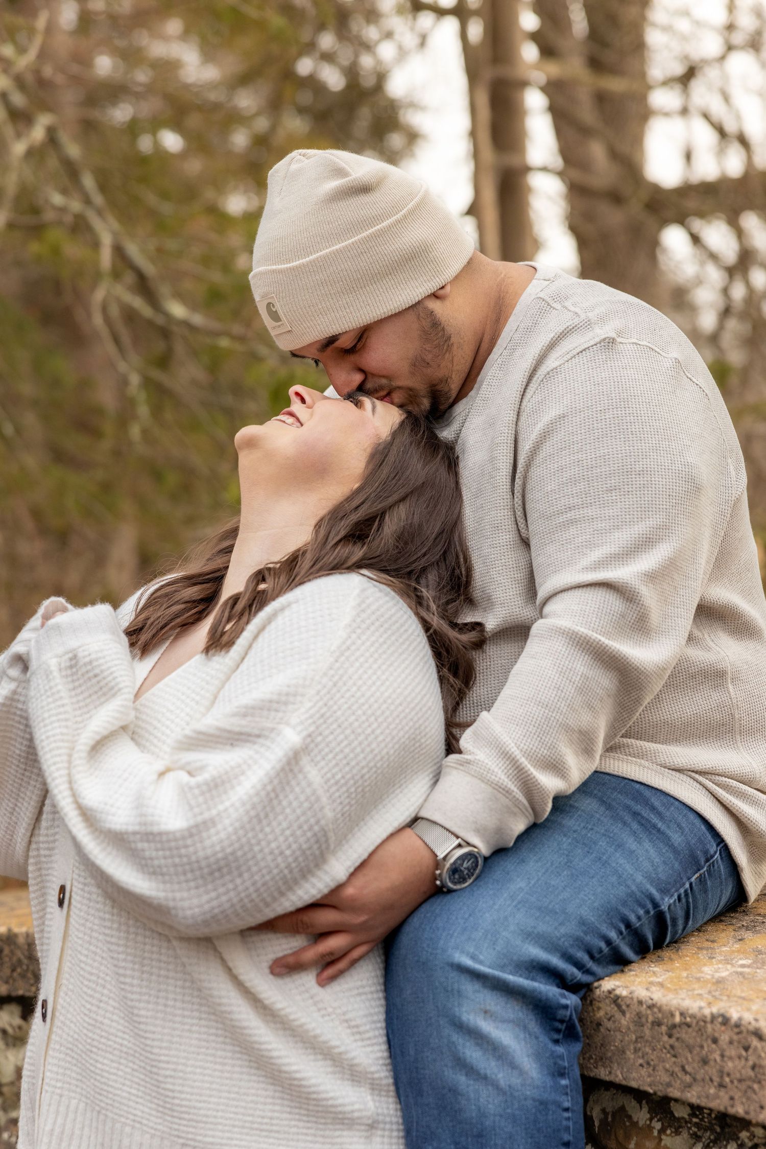 A couple in matching white sweaters shares a romantic moment while sitting outdoors.