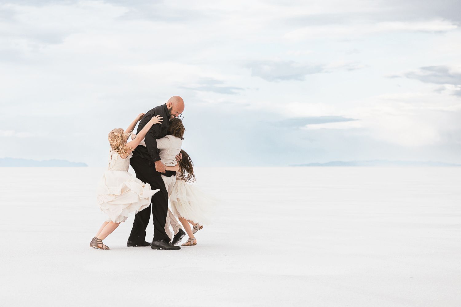 Two people dancing together on a striking white landscape under cloudy skies.