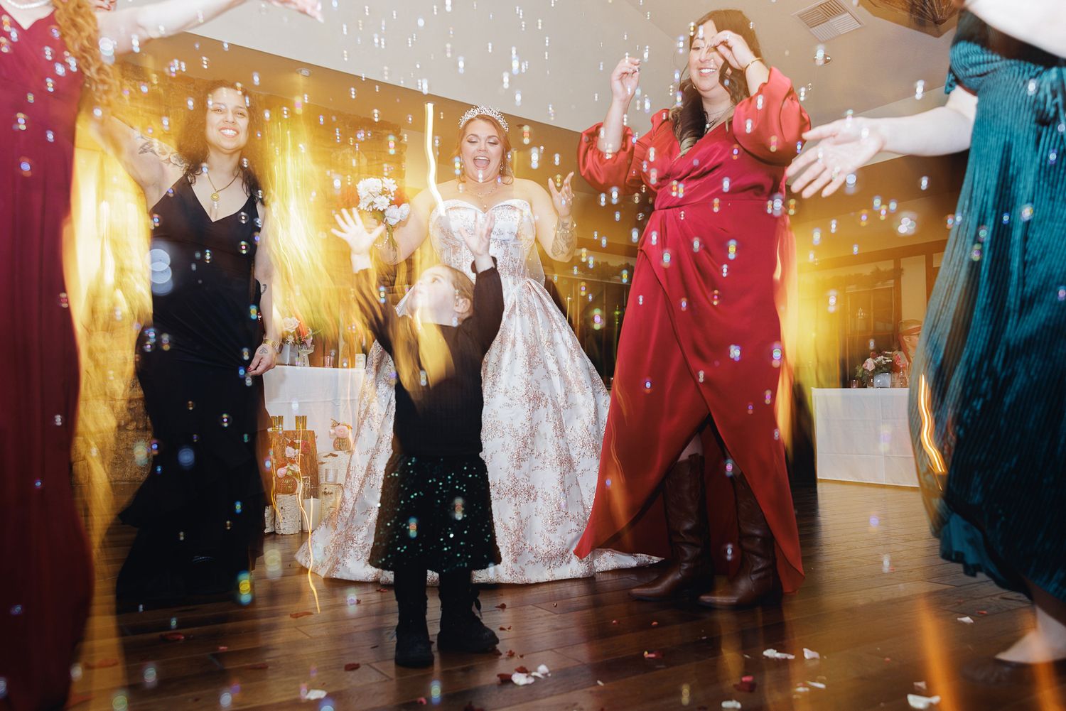Wedding party dancing under sparkling lights and confetti during a celebration.