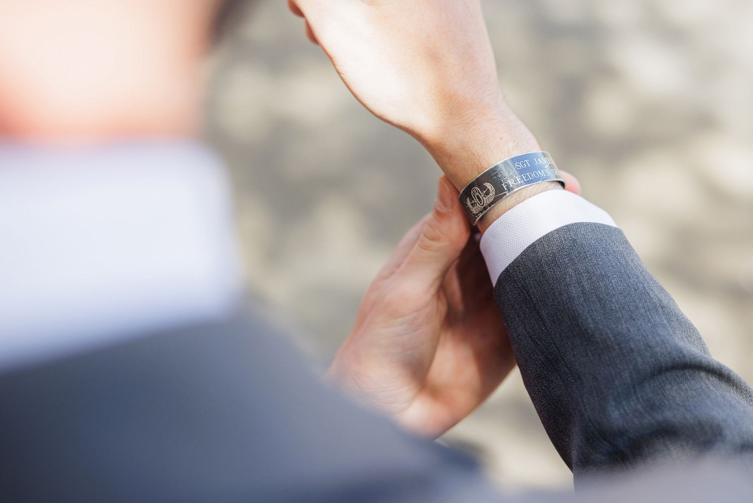 Close-up of a man in a gray suit adjusting a sleek smartwatch on his wrist outdoors.