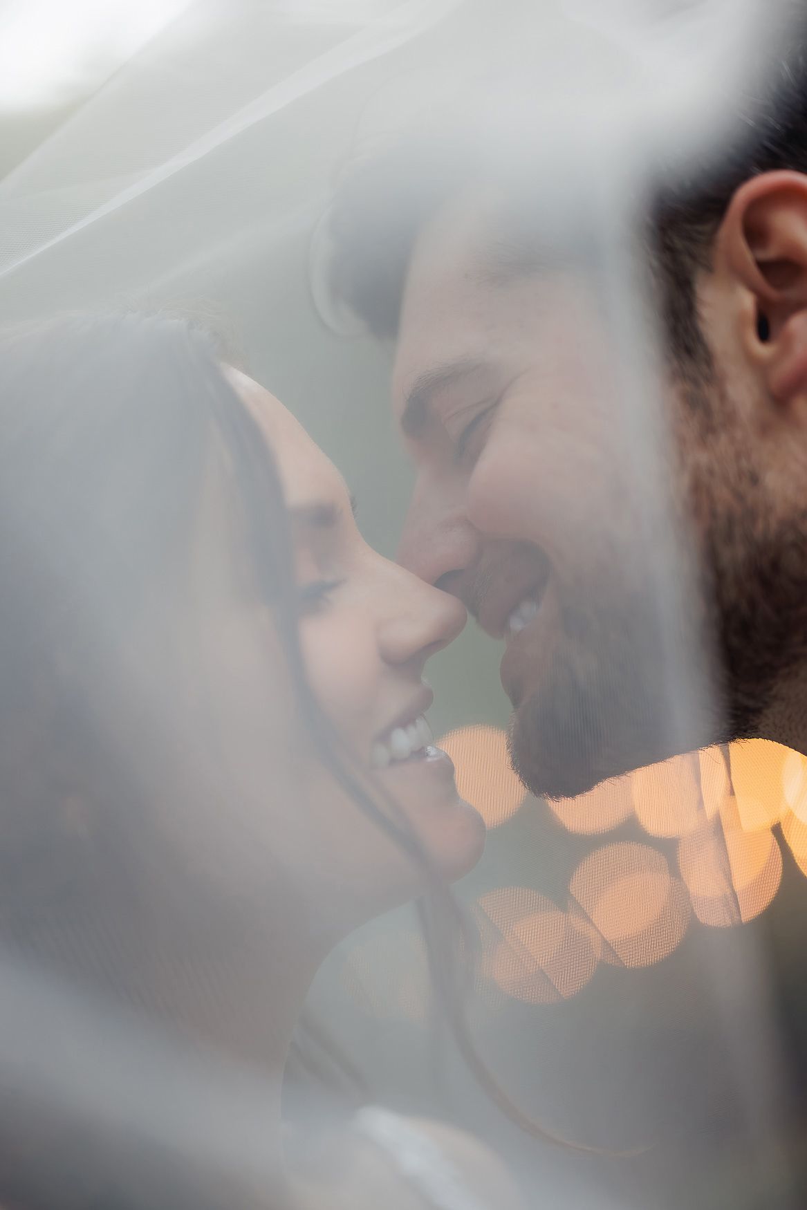A romantic couple share an intimate moment behind steamy glass with soft bokeh lights in the background.