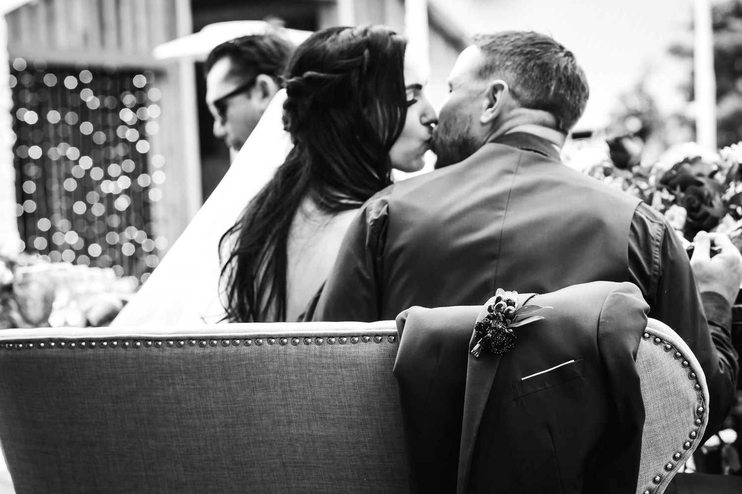 Black and white photo of a couple seated together in a formal setting with decorative lights visible in background.