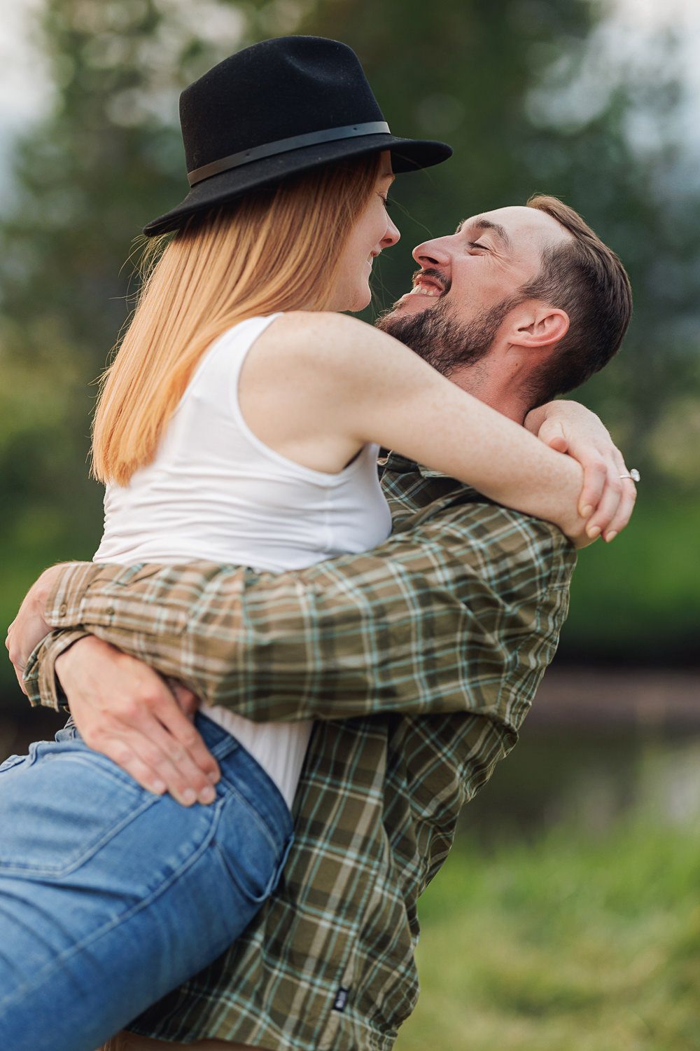 Couple in casual wear sharing a romantic embrace outdoors with a natural green background.