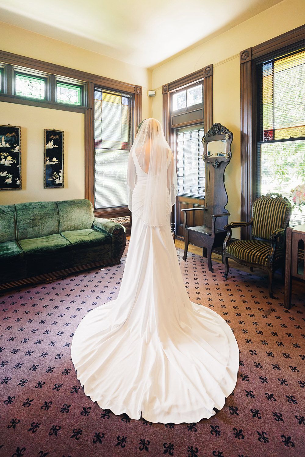 A stunning white wedding dress displayed in various angles on a mannequin against patterned carpet in a sunlit room.