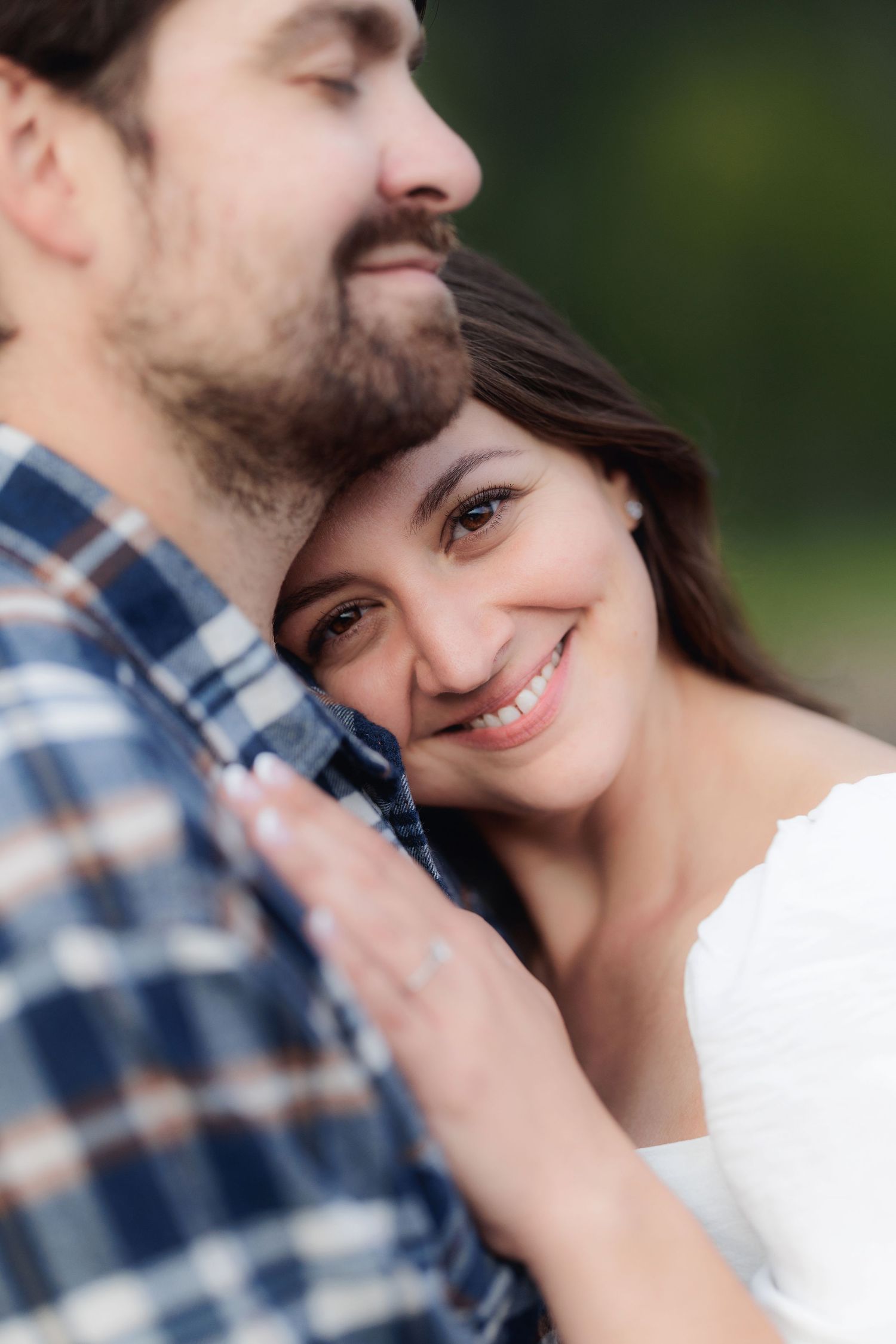 A tender romantic moment captured between a couple embracing outdoors in soft focus.