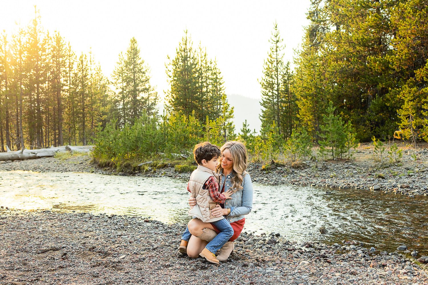 Engaged couple sharing romantic moments during a golden hour photo session in a scenic forest setting.