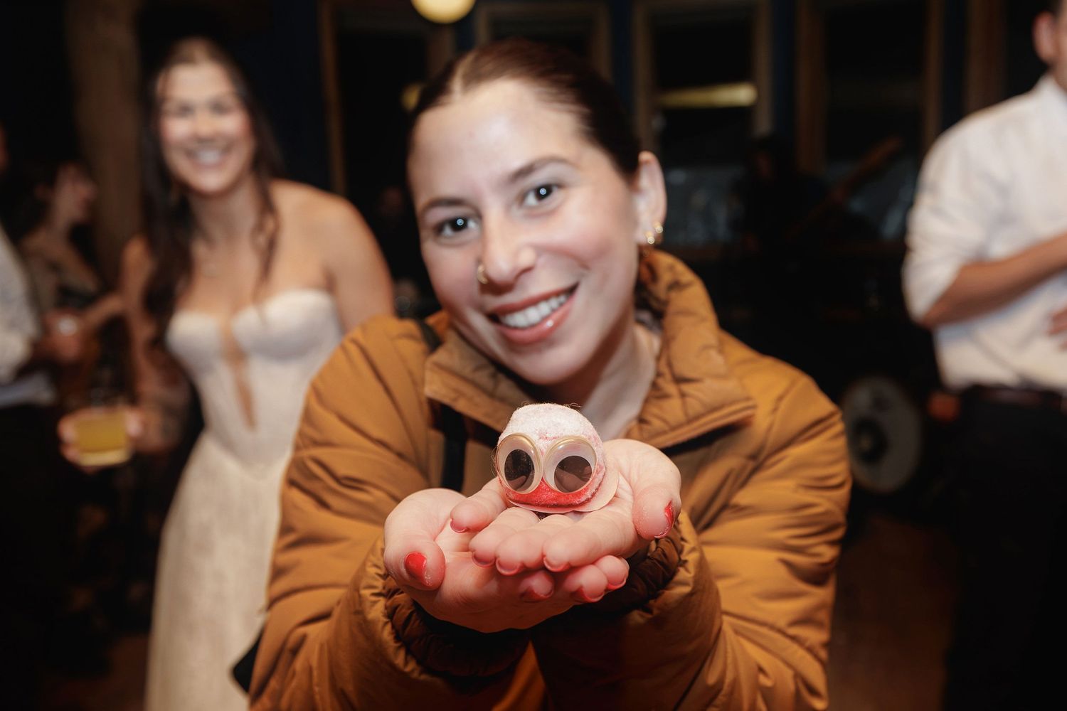 Woman smiling holding small ghost-shaped treat at festive wedding celebration event.