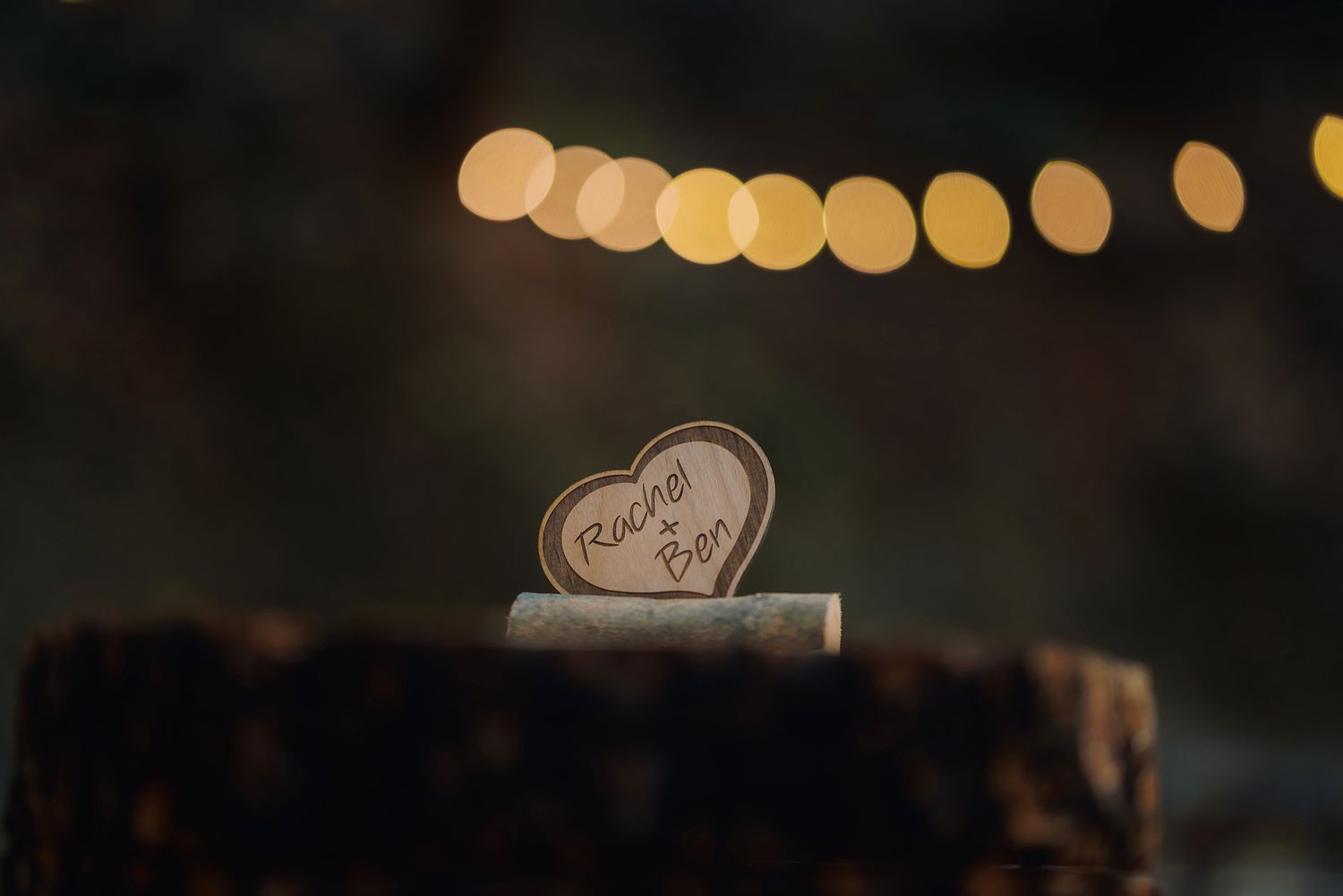 A heart-shaped piece on a wooden surface with blurred golden bokeh lights in the background.