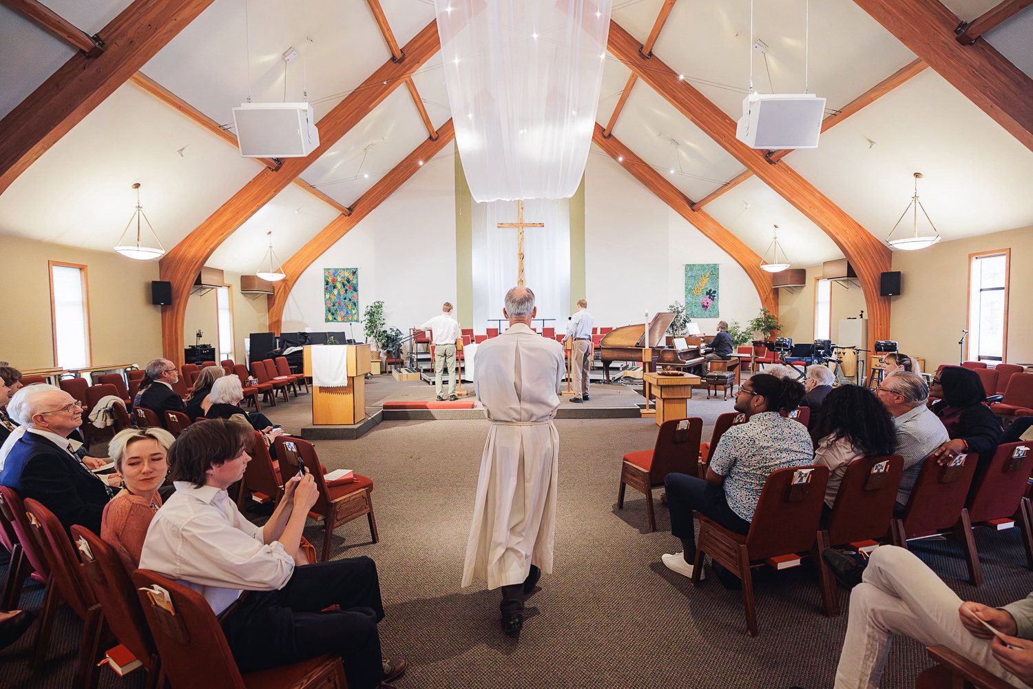 People gathered in a church hall with exposed wooden beams and white walls for a community event.