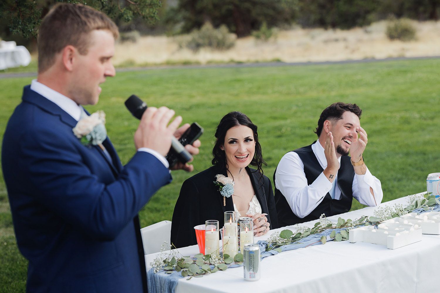 Speech at an outdoor wedding reception table showing emotional reactions from guests during dinner toasts.